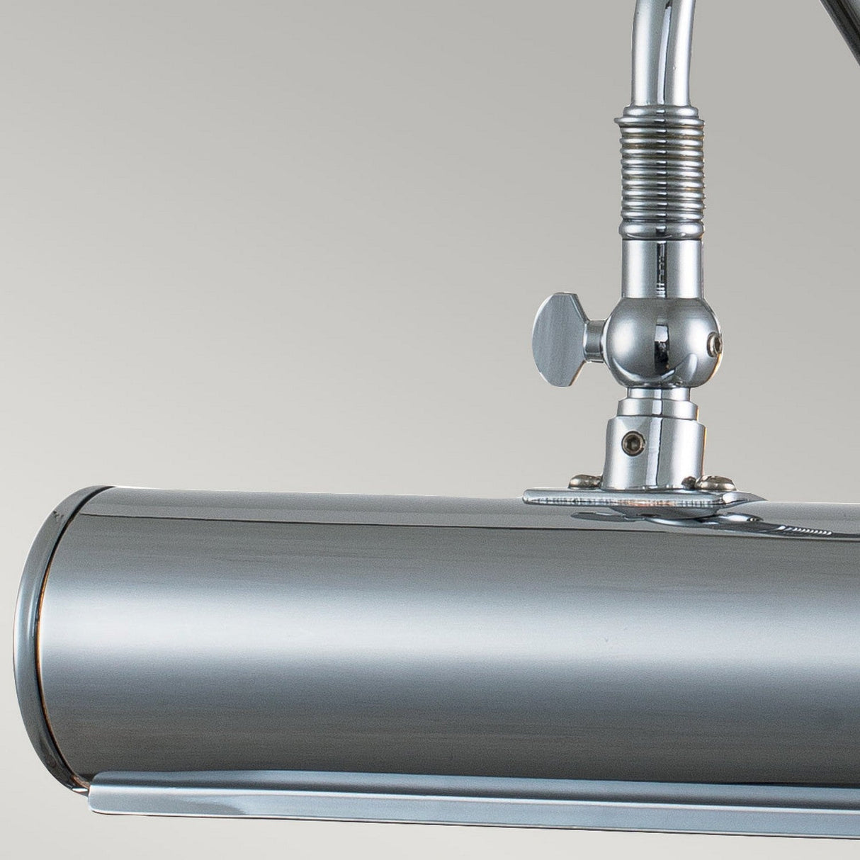 Close-up of a Picture Light 1 Light Small in polished chrome, showcasing its modern metallic ceiling fixture. The cylindrical design features a shiny, reflective surface, curved edges, and an adjustable pivot joint on a neutral background, making it an ideal modern lighting solution.