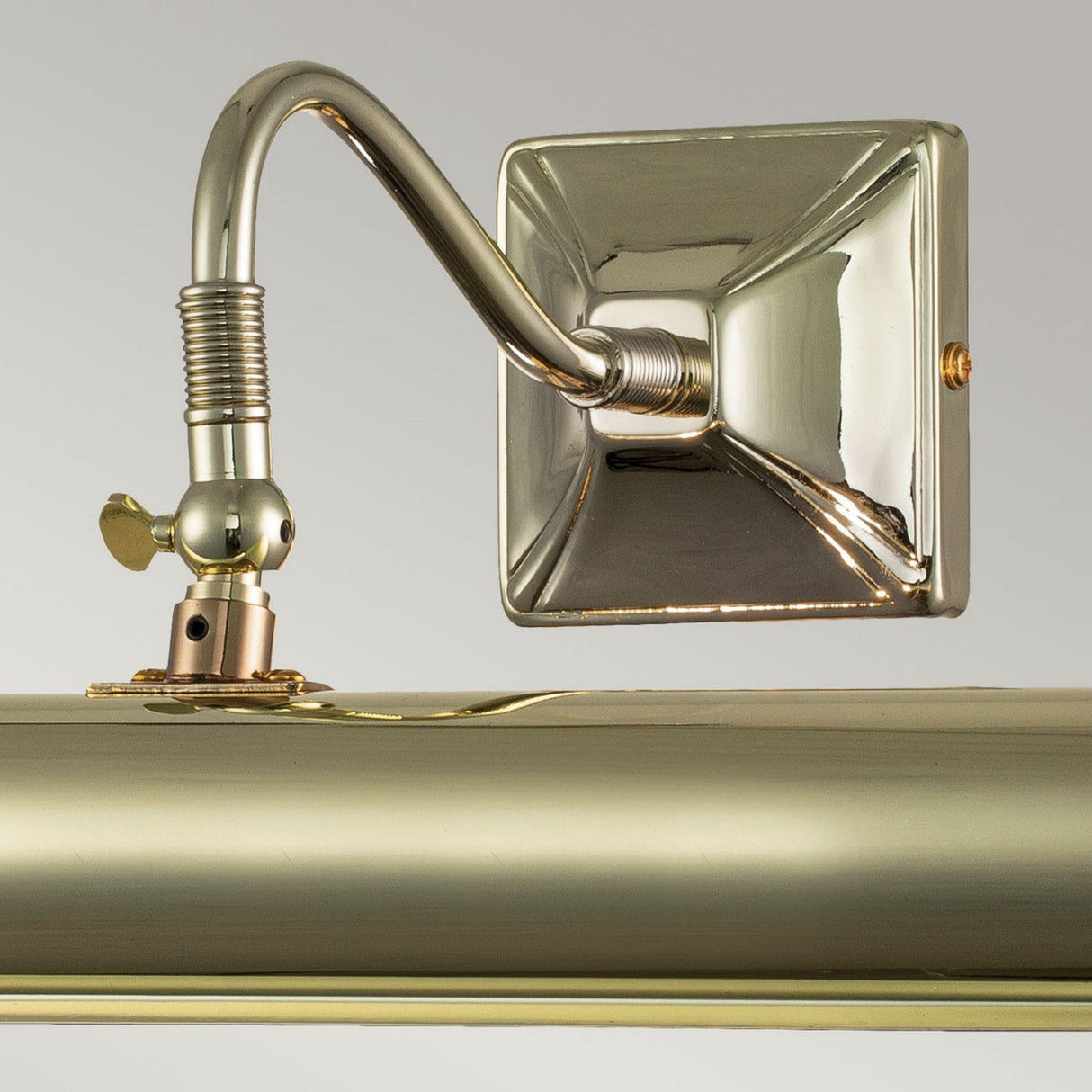 A close-up of the Picture Light 2 Light Large in polished brass showcases its stylish curved arm and square base. This lamp elegantly reflects light, offering perfect illumination for artwork while enhancing its elegant design.