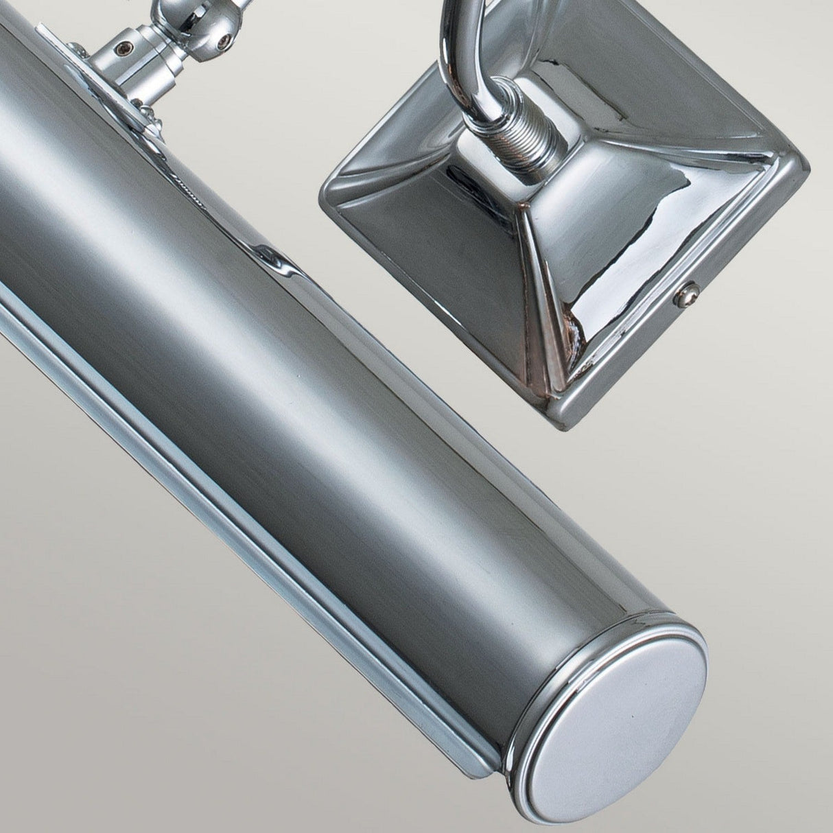 A close-up of the Picture Light 2 Light Large in polished chrome showcases its modern design with a sleek rectangular base and cylindrical lamp. Its adjustable arm ensures precise light direction against a plain background.
