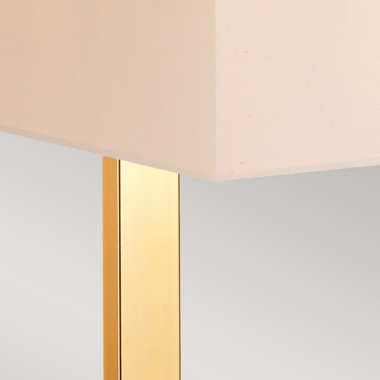Close-up of the Plein 1 Light Table Lamp featuring a beige rectangular lampshade atop a sleek, polished gold stand. The softly blurred background highlights the minimalist design and smooth texture of this elegant piece, ideal for modern decor enthusiasts who appreciate its sophisticated dark brown and polished gold accents.