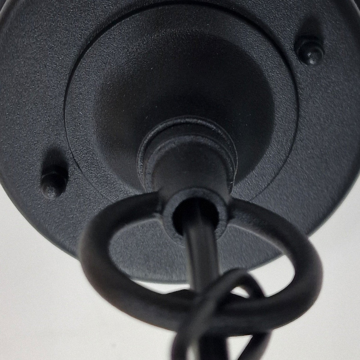 The Parish 1 Light Outdoor Chain Pendant - Black is a vintage charm made from premium die-cast aluminum. It boasts a circular base with a central looped wire, enhanced by a textured surface and three small screw heads, enhancing its appeal as an outdoor chain pendant.