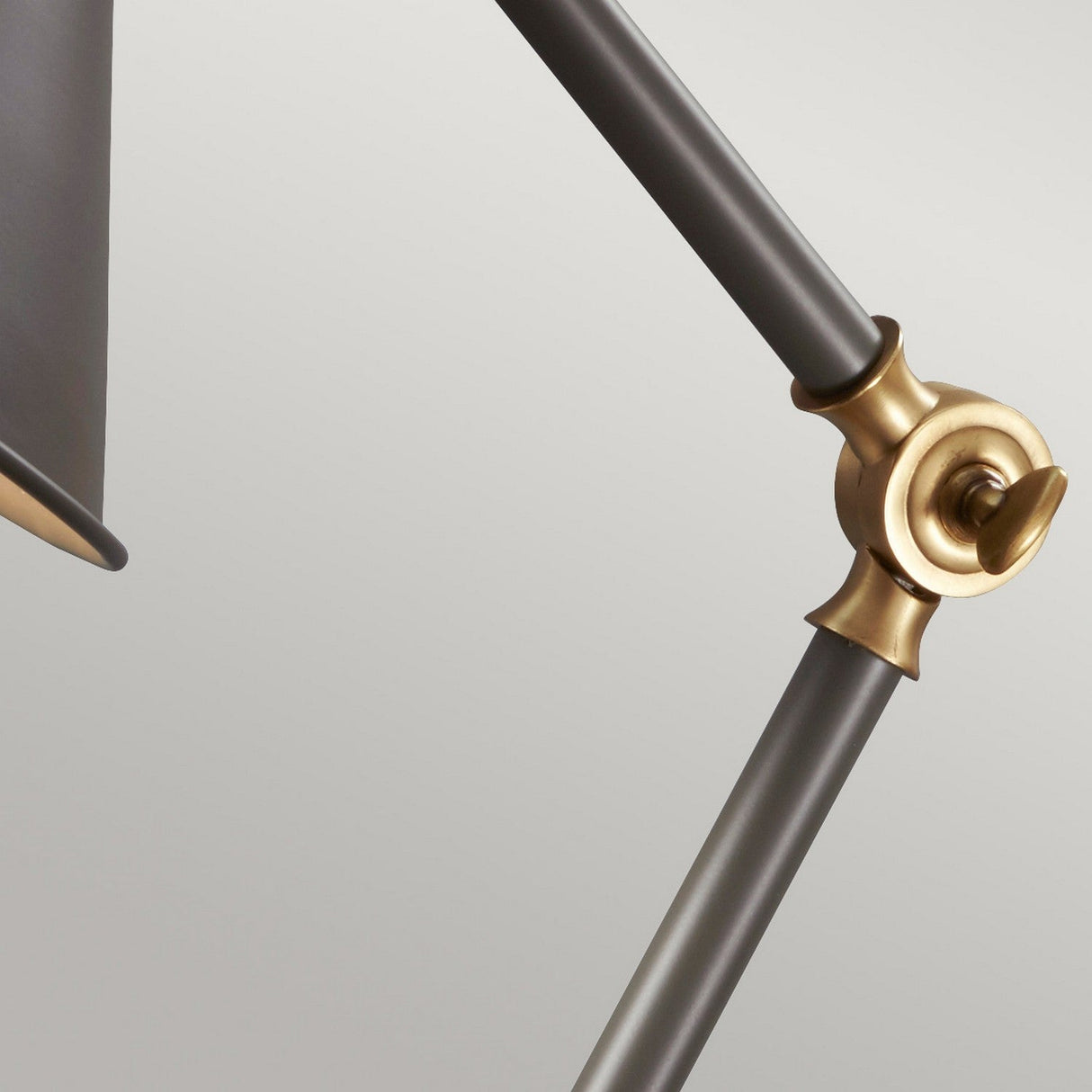 Close-up of the Provence Element 1 Light Mini Table Lamp, showcasing its dark grey shade and aged brass joint set against a light gray background, blending vintage and modern design elements.