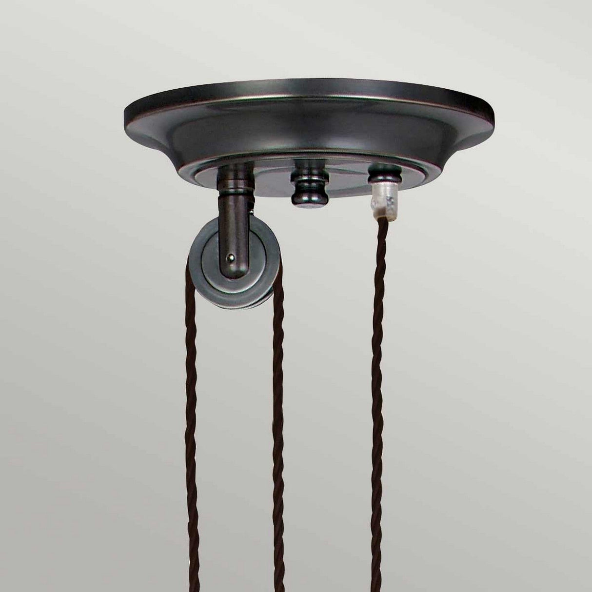 The Provence 1 Light Rise & Fall Pendant - Old Bronze boasts a vintage-style design with a dark old bronze circular base and two elegant twisted brown cords. These cords attach gracefully to a decorative metal hook on the ceiling plate, enhancing its French design charm against a neutral background.