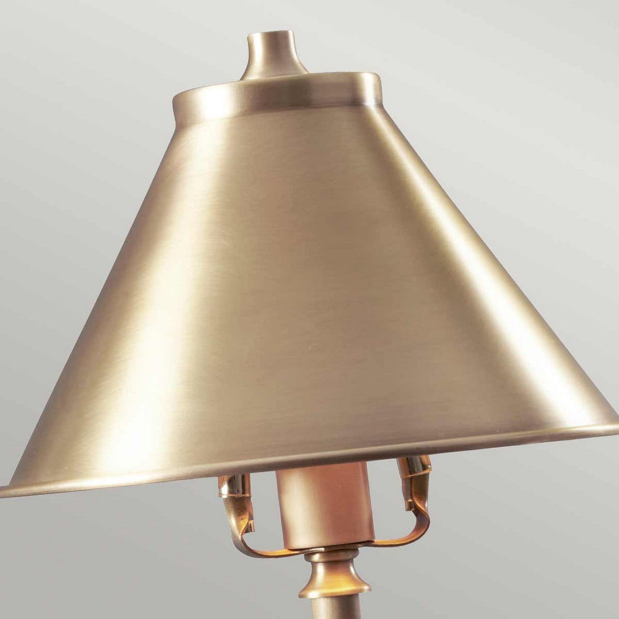 The Provence 1 Light Stick Lamp in aged brass features a conical shade. This compact lamp showcases a brushed gold finish, with its simple and elegant French design beautifully set against a plain, light gray background.