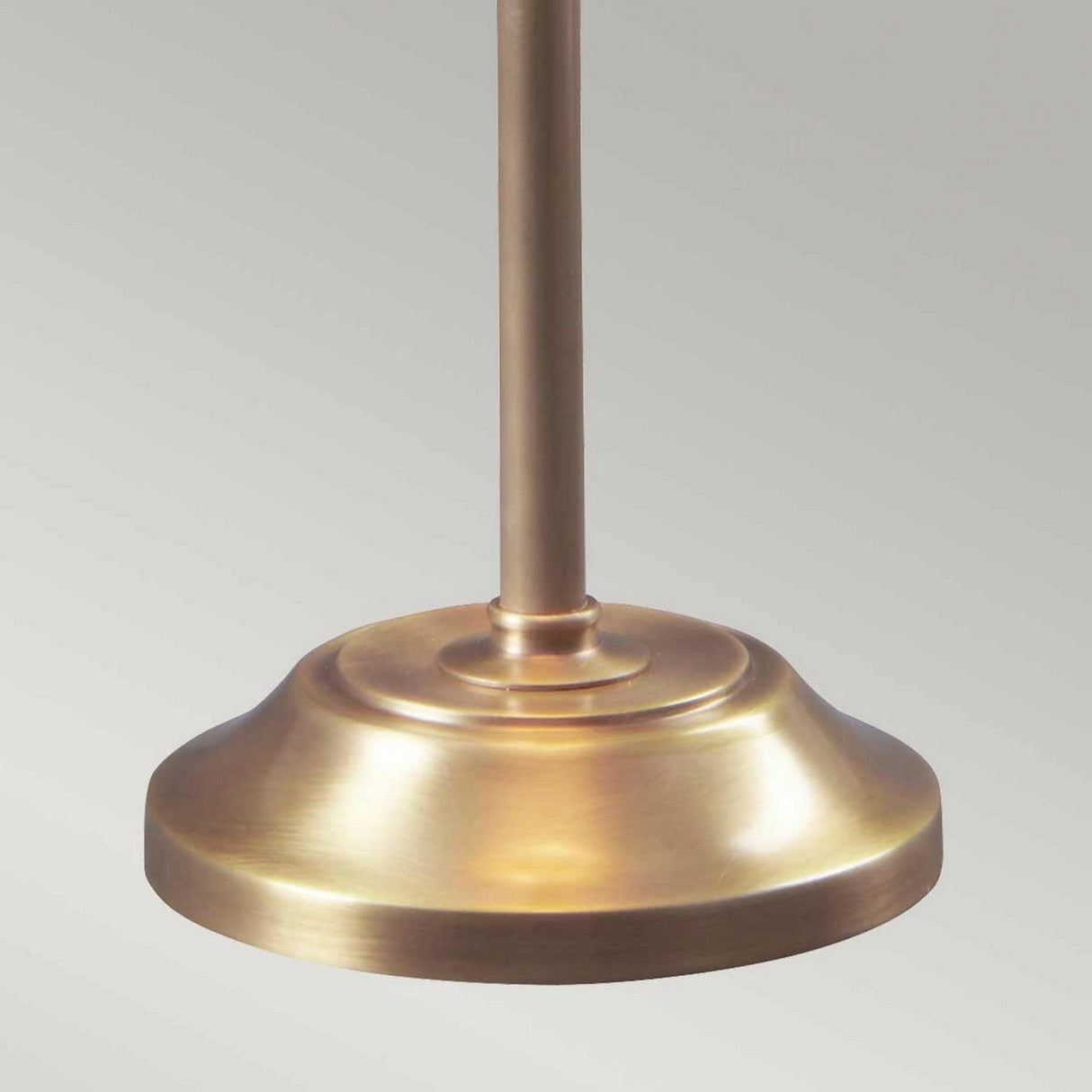 The image features the base of the Provence 1 Light Stick Lamp in aged brass, highlighting its smooth, slightly brushed finish and a cylindrical support pole that extends upwards. The lamp embodies a refined French Design Lighting aesthetic against a plain light grey background.