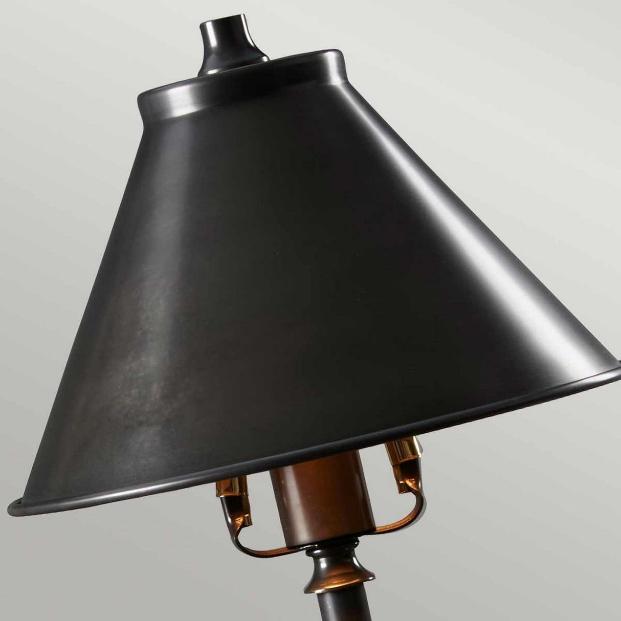 A close-up of the Provence 1 Light Stick Lamp features a black metal lampshade with a smooth, conical shape and an old bronze finish. The lamp holder and part of its structure are visible, casting ambient downlighting against a neutral background.