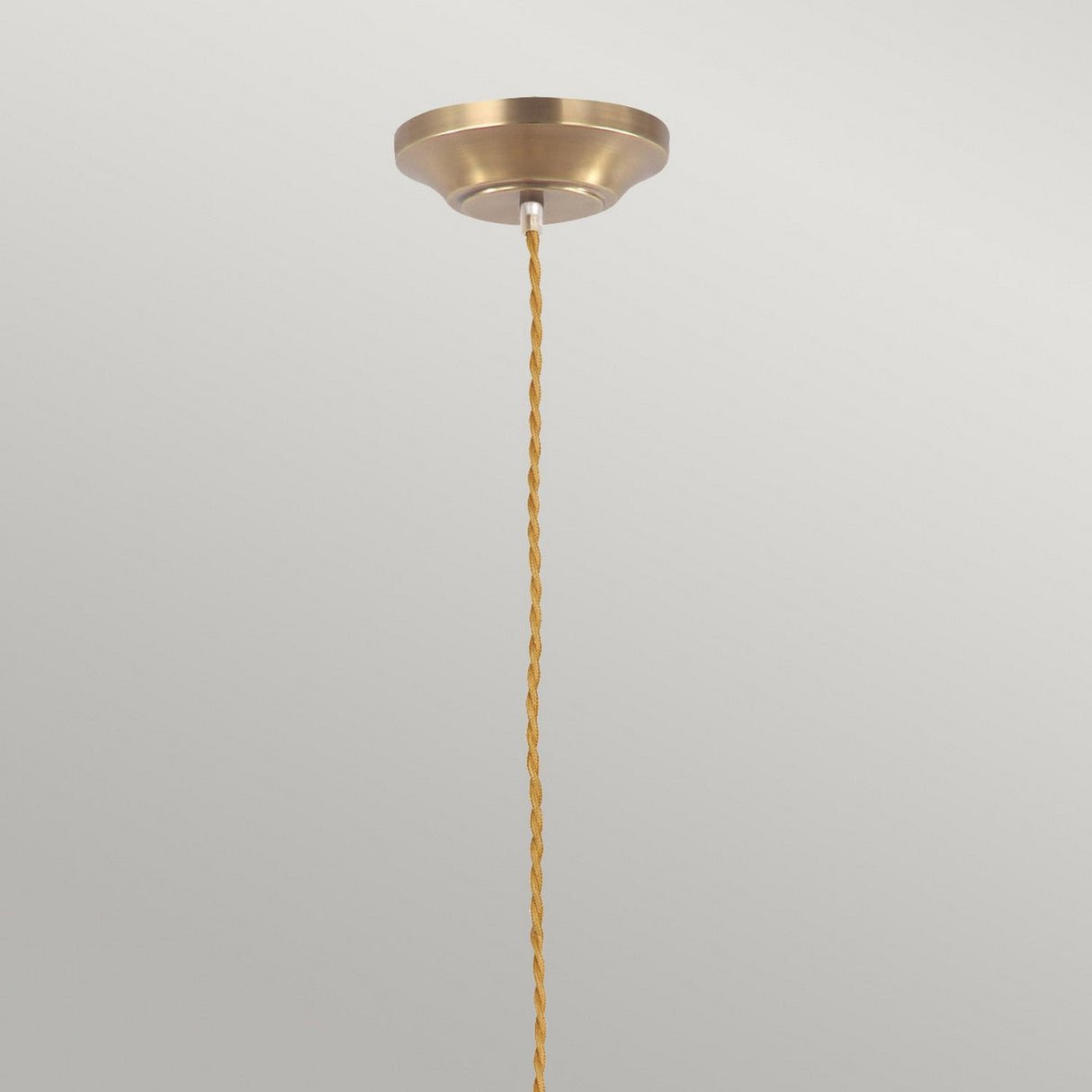 The Provence 1 Light Pendant in aged brass exudes vintage charm with its twisted brown fabric electrical cord, contrasting beautifully against a light gray background. Its simple and elegant design highlights a modern minimalist aesthetic.