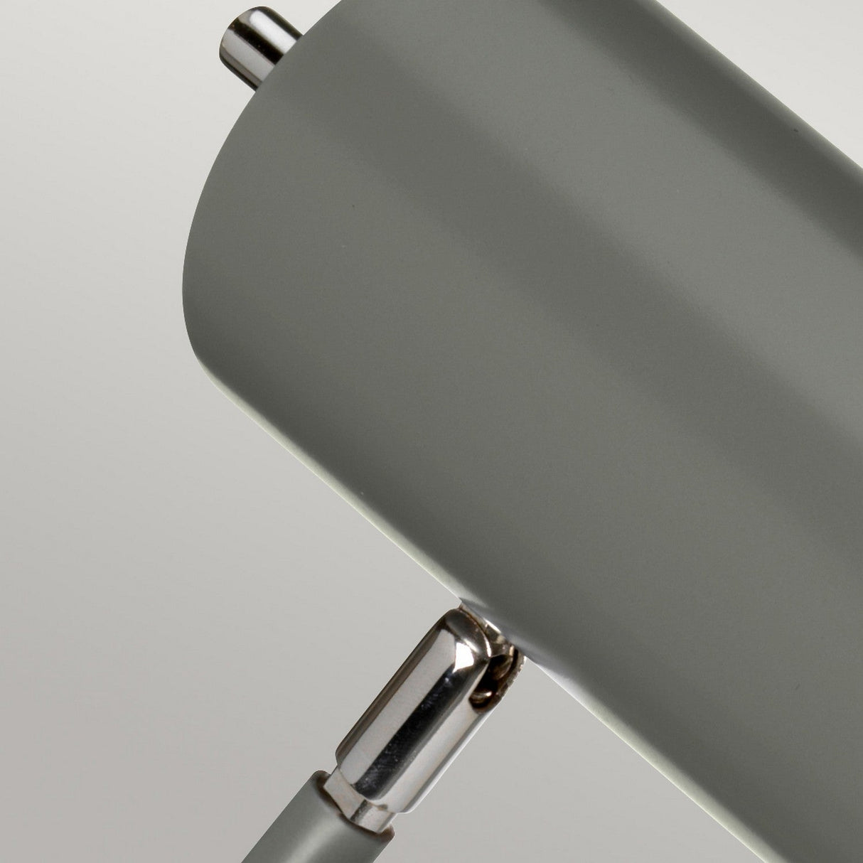 Close-up of the Quinto 1 Light Table Lamp in dark grey and polished nickel, featuring a modern cylindrical design. With its adjustable head, metallic joints, and matte finish, this lamp is perfect for industrial-style interiors. It is set against a neutral background to highlight its stylish connection between the lamp body and stand.