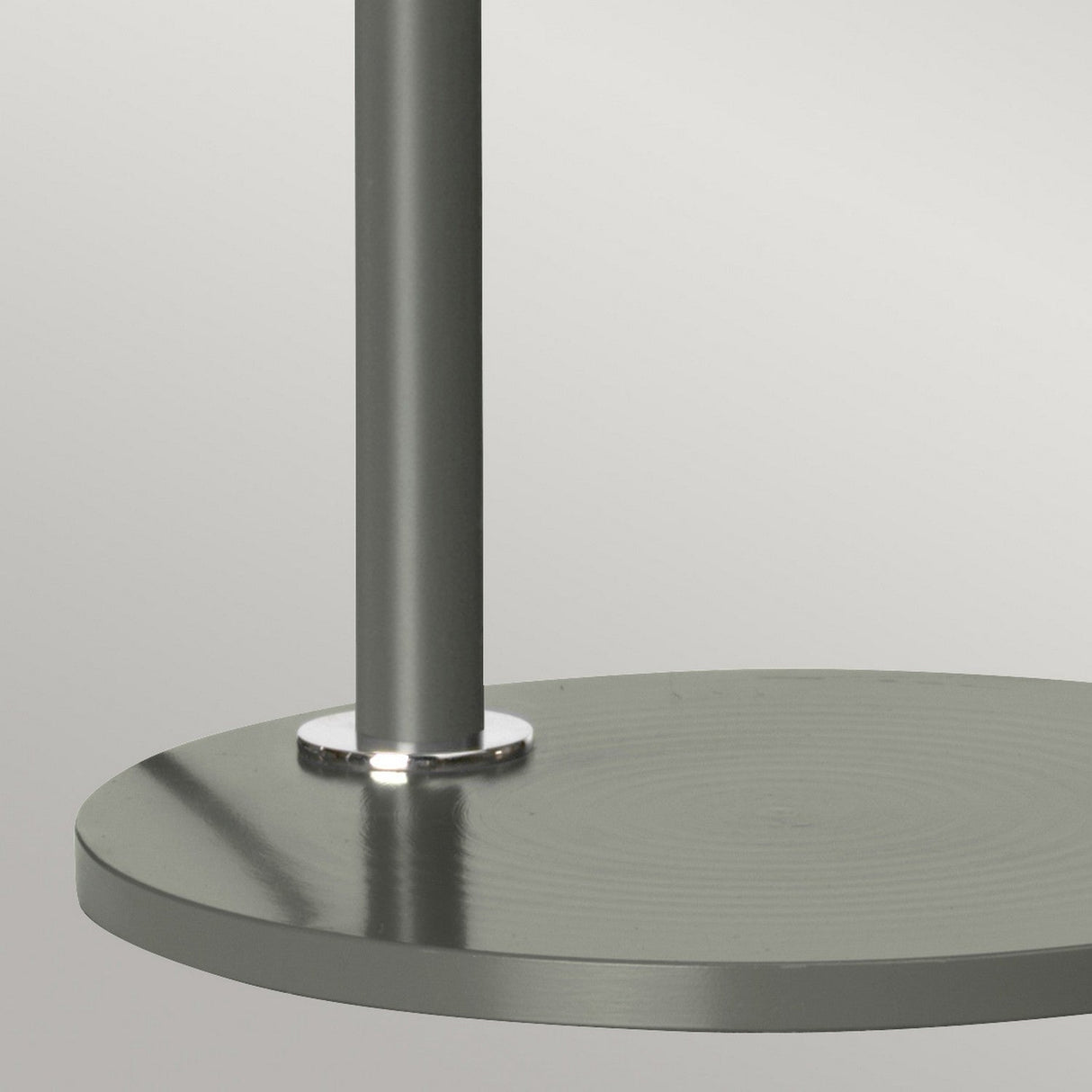 Close-up of the Quinto 1 Light Table Lamp, featuring a modern cylindrical base in dark grey with a polished nickel vertical pole. Its adjustable head provides versatility, and the smooth surface subtly reflects light. The neutral gray background enhances its minimalist design, making it an ideal choice for industrial-style interiors.