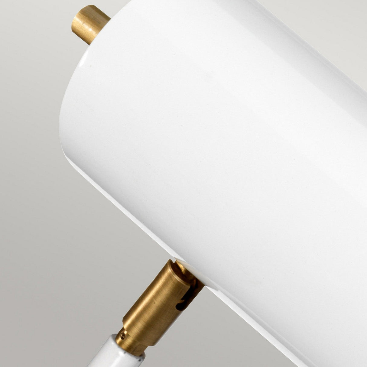 Close-up of the Quinto 1 Light Table Lamp - White/Aged Brass, a contemporary design characterized by an aged brass and white finish. The lamp features a cylindrical shade connected to a metallic joint, highlighting its minimalist design with a clean, smooth surface and warm metallic accents.