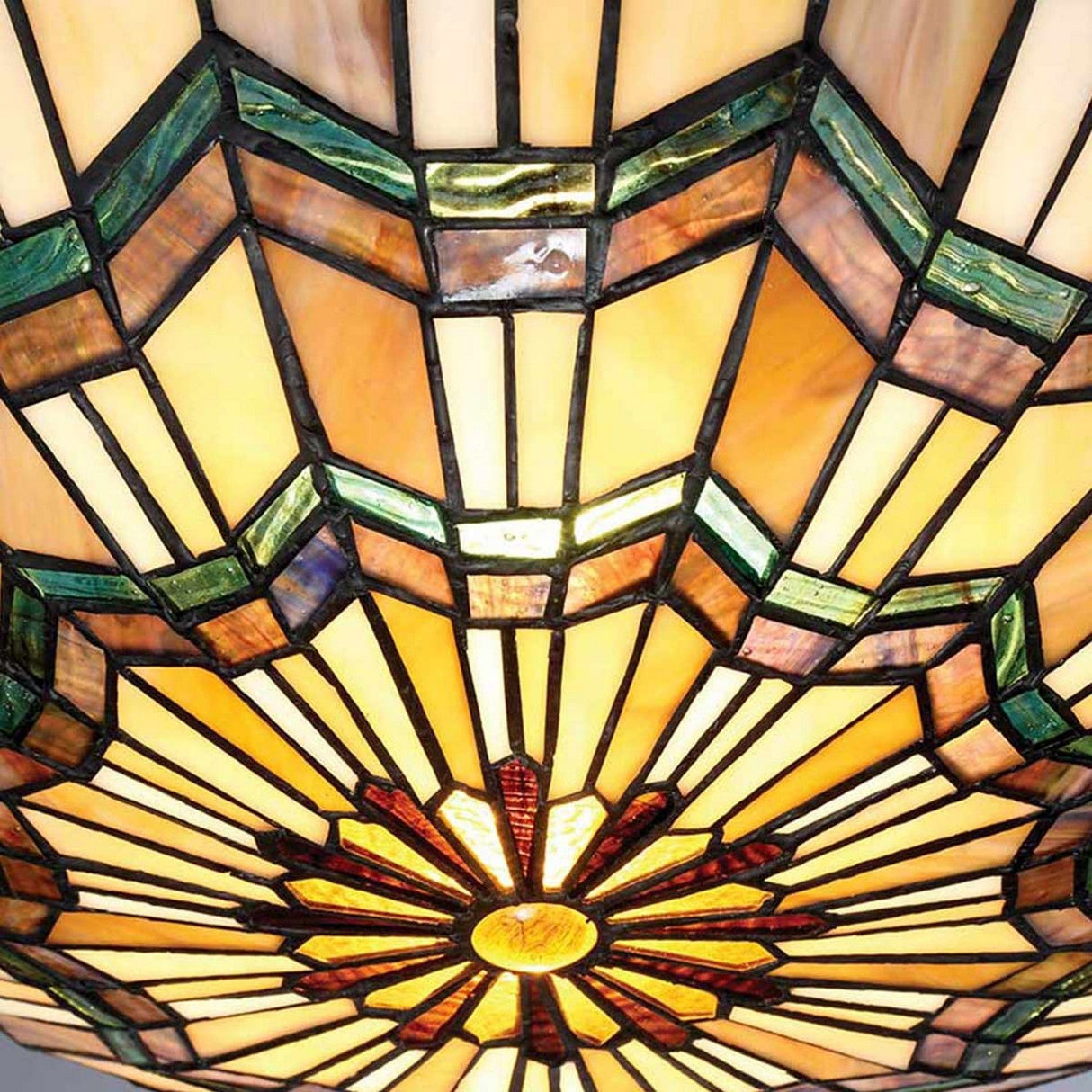 The Alcott 2 Light Tiffany Flush in Valiant Bronze features a stained glass lampshade adorned with geometric patterns in warm hues of yellow, green, and red, emanating from a central floral motif. Echoing the Arts and Crafts movement, its intricate design produces a vibrant, colorful display that highlights timeless craftsmanship.