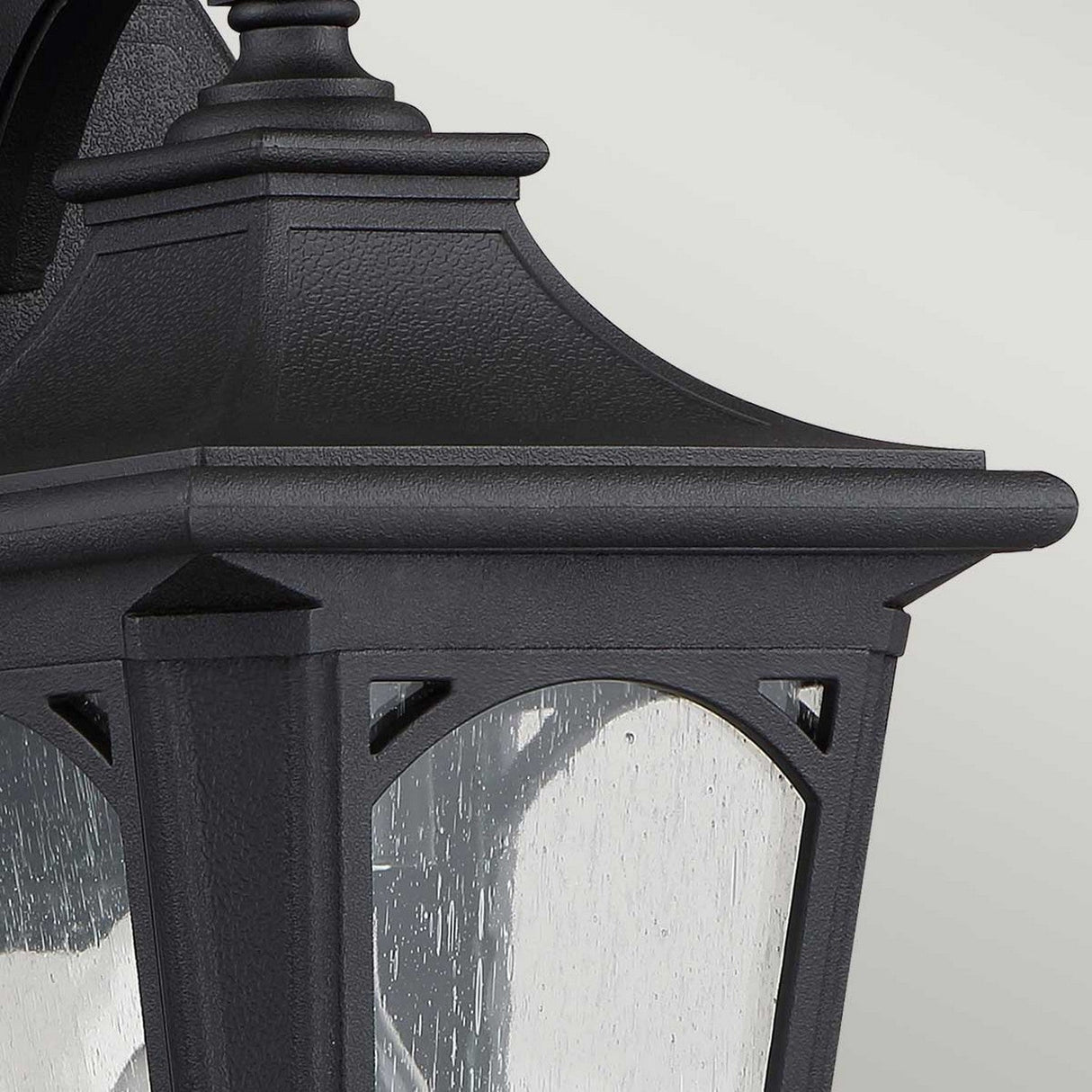 Close-up of the Bedford Outdoor 1 Light Small Wall Lantern in black, showcasing its vintage rectangular design and clear glass panels. Made from durable composite material, the lantern boasts a textured finish against a soft, neutral background.