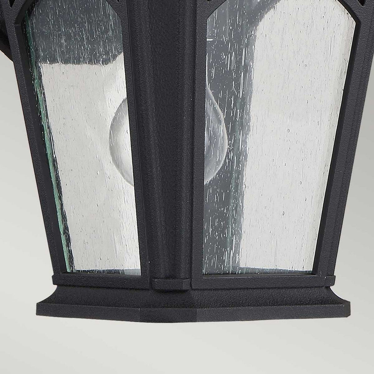 A detailed view of the Bedford Outdoor 1 Light Small Wall Lantern in black, featuring clear glass panes and a visible light bulb inside, made from durable composite material, against a neutral background.