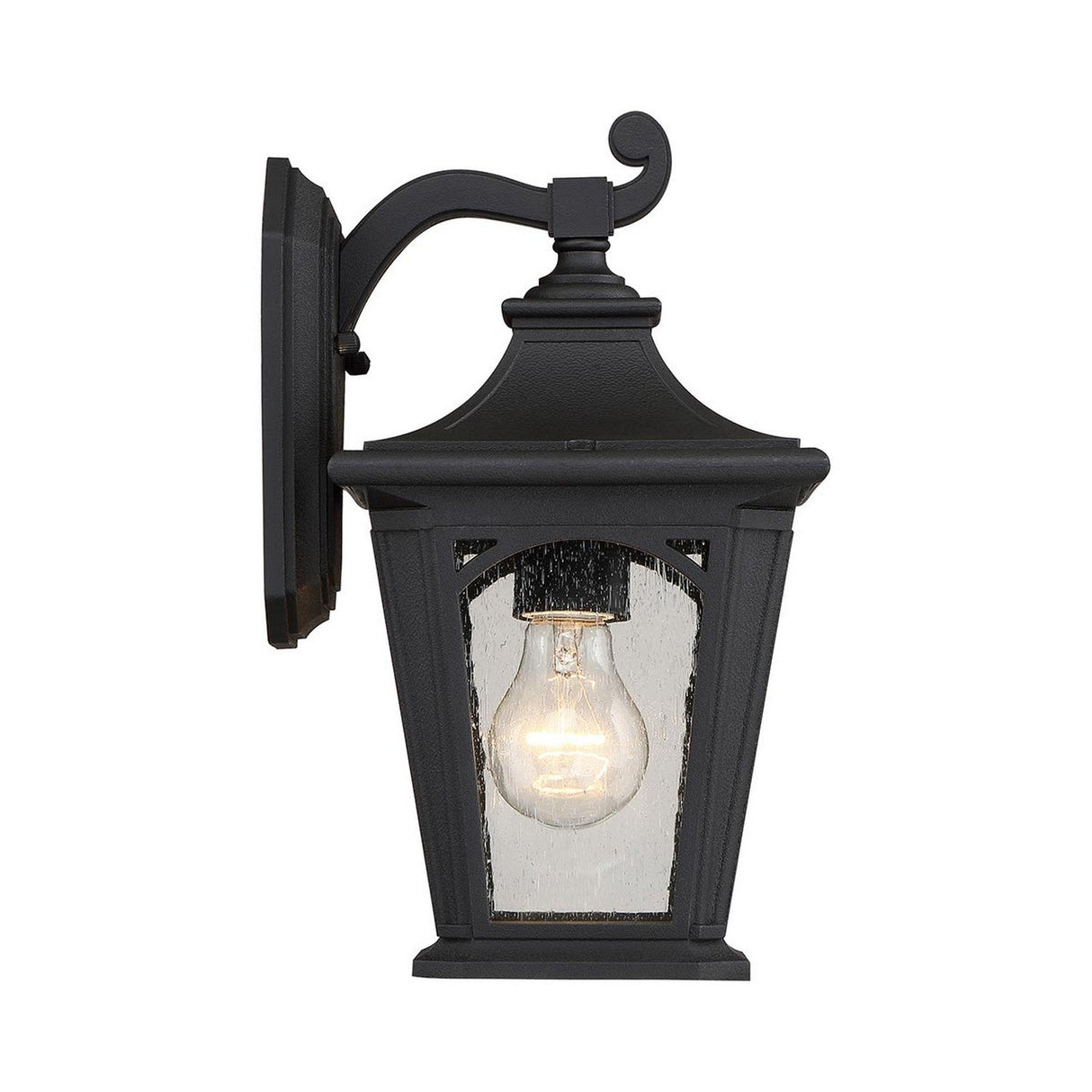 The Bedford Outdoor 1 Light Small Wall Lantern in black showcases a vintage style with its durable composite construction, classic design, clear glass panels, and a visible lit bulb inside, all gracefully mounted on a decorative curved arm.