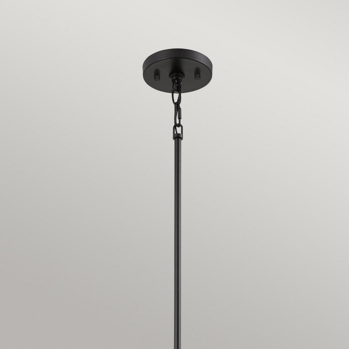 The Bismarck 1 Light Mini Pendant - Black features a geometric flair with its black rod design, hanging elegantly from a ceiling. It includes a round base and chain link, set against a plain white background to emphasize its sleek metal construction and offer subtle ambient lighting.