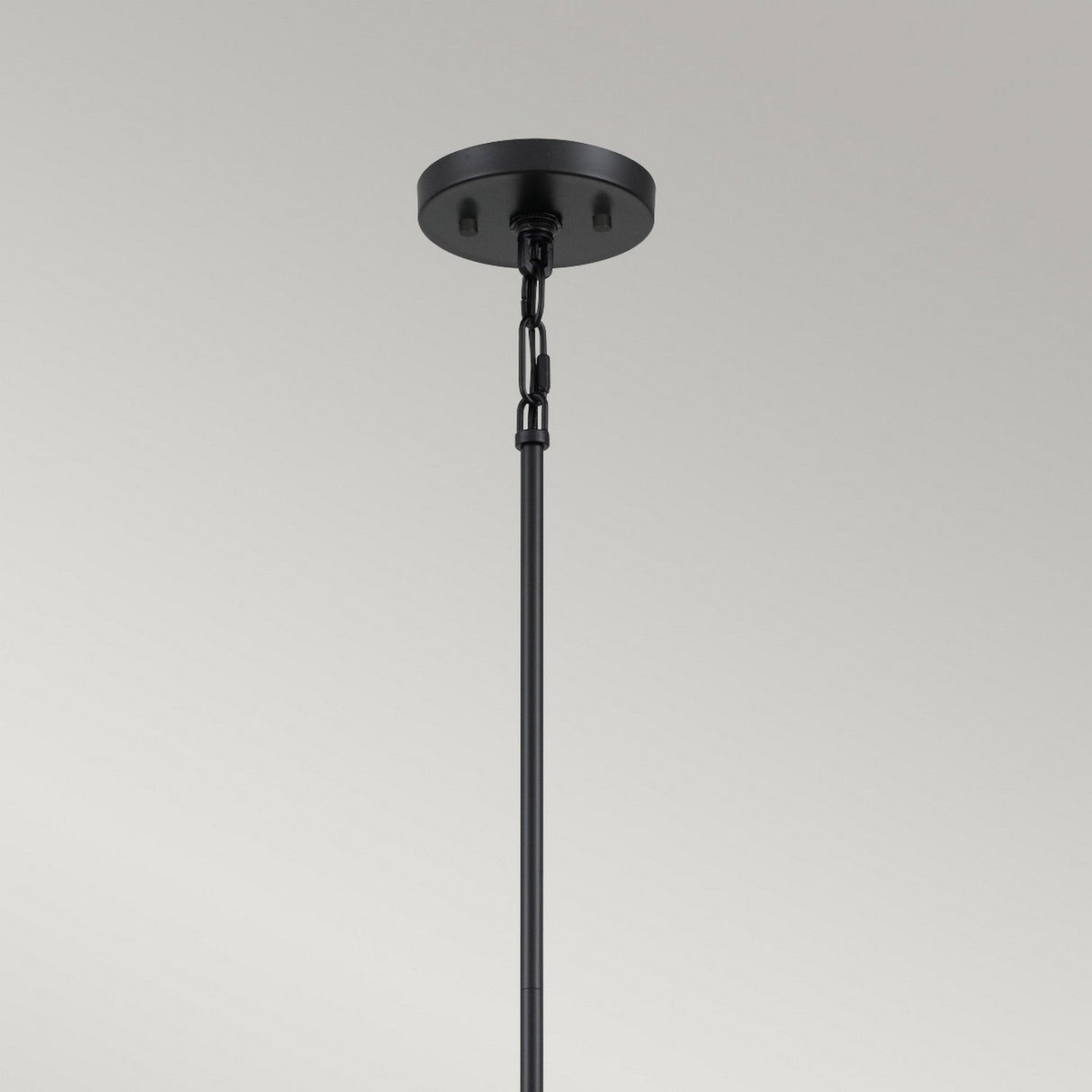 A black ceiling light fixture featuring a round base and a chain link connecting to a rod, exuding modern geometric design, stands against a gray background. Its sleek black finish mirrors the elegance of the Bismarck 5 Light Chandelier - Black.