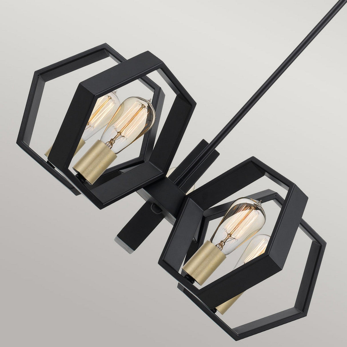 Introducing the Bismarck 5 Light Chandelier - Black, a modern light fixture showcasing sleek black finishes and an eye-catching geometric design. It features two black hexagonal frames, each supporting an exposed bulb with a brass socket, connected by a central black rod set against a neutral background.