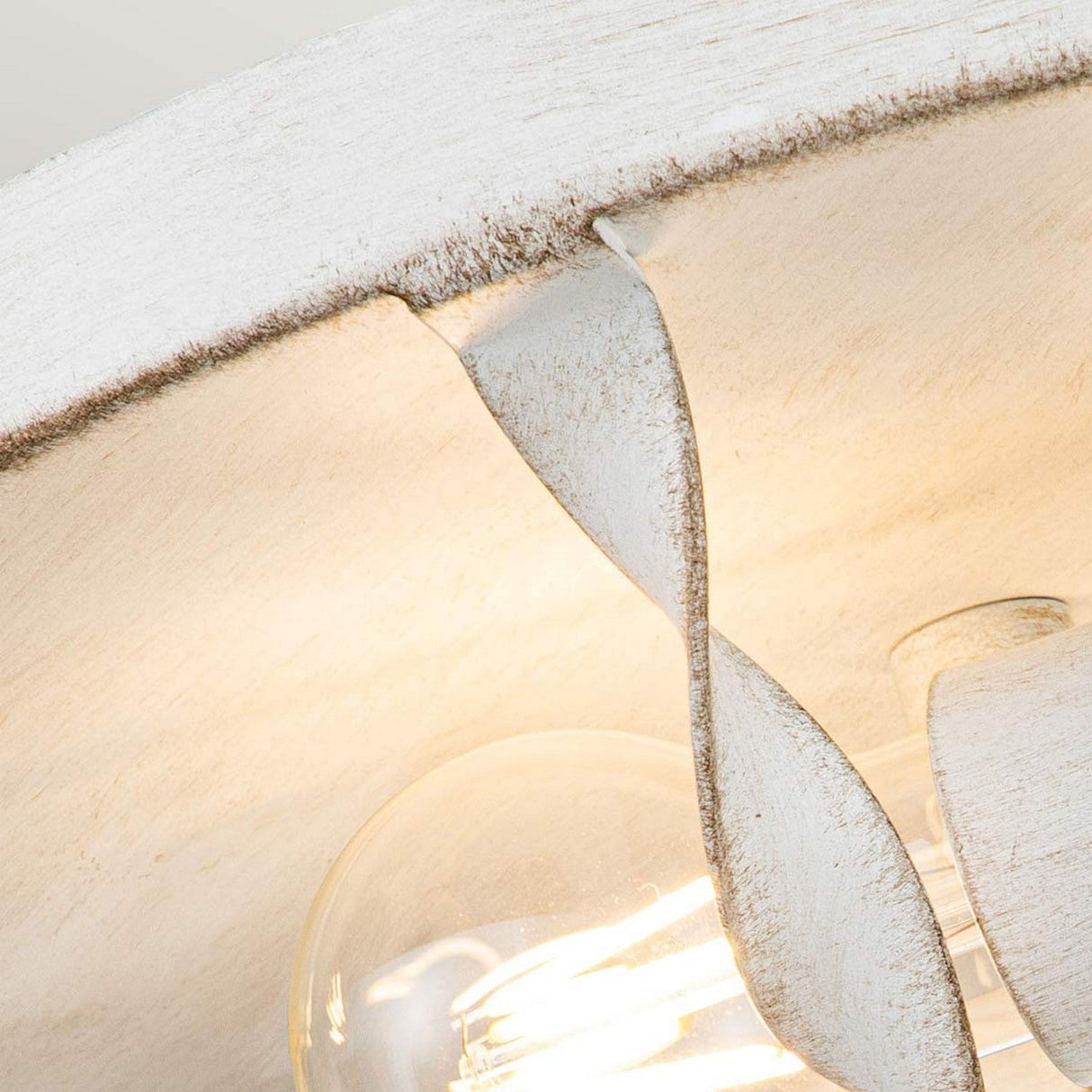 Here's a revised sentence using the given product data:
A close-up of the Bradbury 2 Light Flush in Antique White, showcasing its exposed bulbs and textured, weathered appearance that enhances its vintage charm. The curled metal detail highlights the craftsmanship of this delightful fixture.