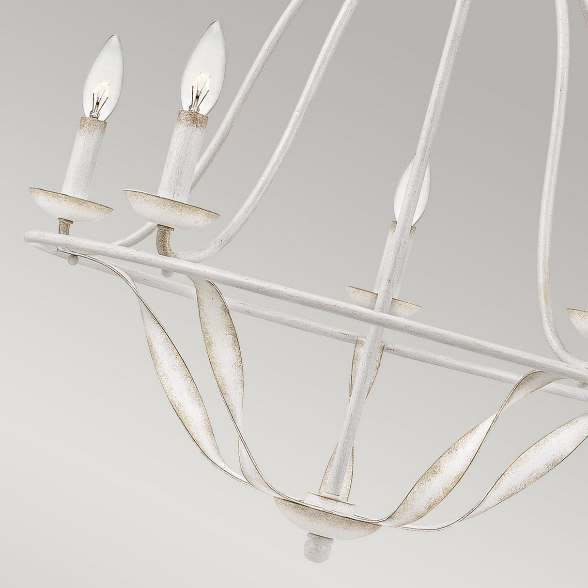 Introducing the Bradbury 5 Light Chandelier in Antique White, featuring a vintage-style design with a distressed finish and three candle-shaped bulbs. Its frame showcases curved arms and leaf-like decorative elements, offering an elegant and rustic appearance that exudes timeless vintage charm against a neutral backdrop.
