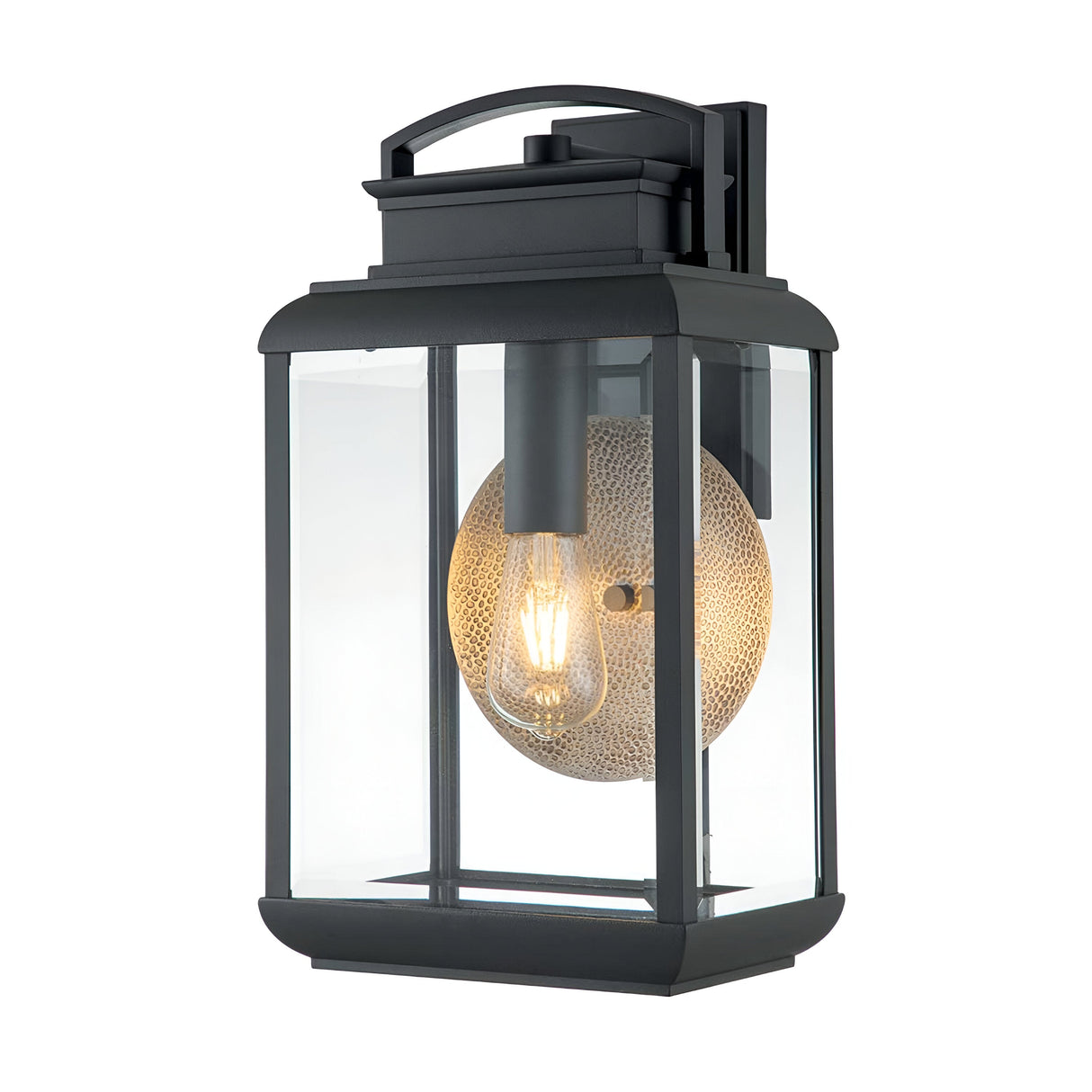 The Byron Outdoor 1 Light Large Wall Lantern features a modern design with a rectangular black metal frame and bevelled glass panels. Inside, a warmly glowing cylindrical light bulb is partially enclosed by a textured, circular metallic screen in graphite finish with a grey reflector.