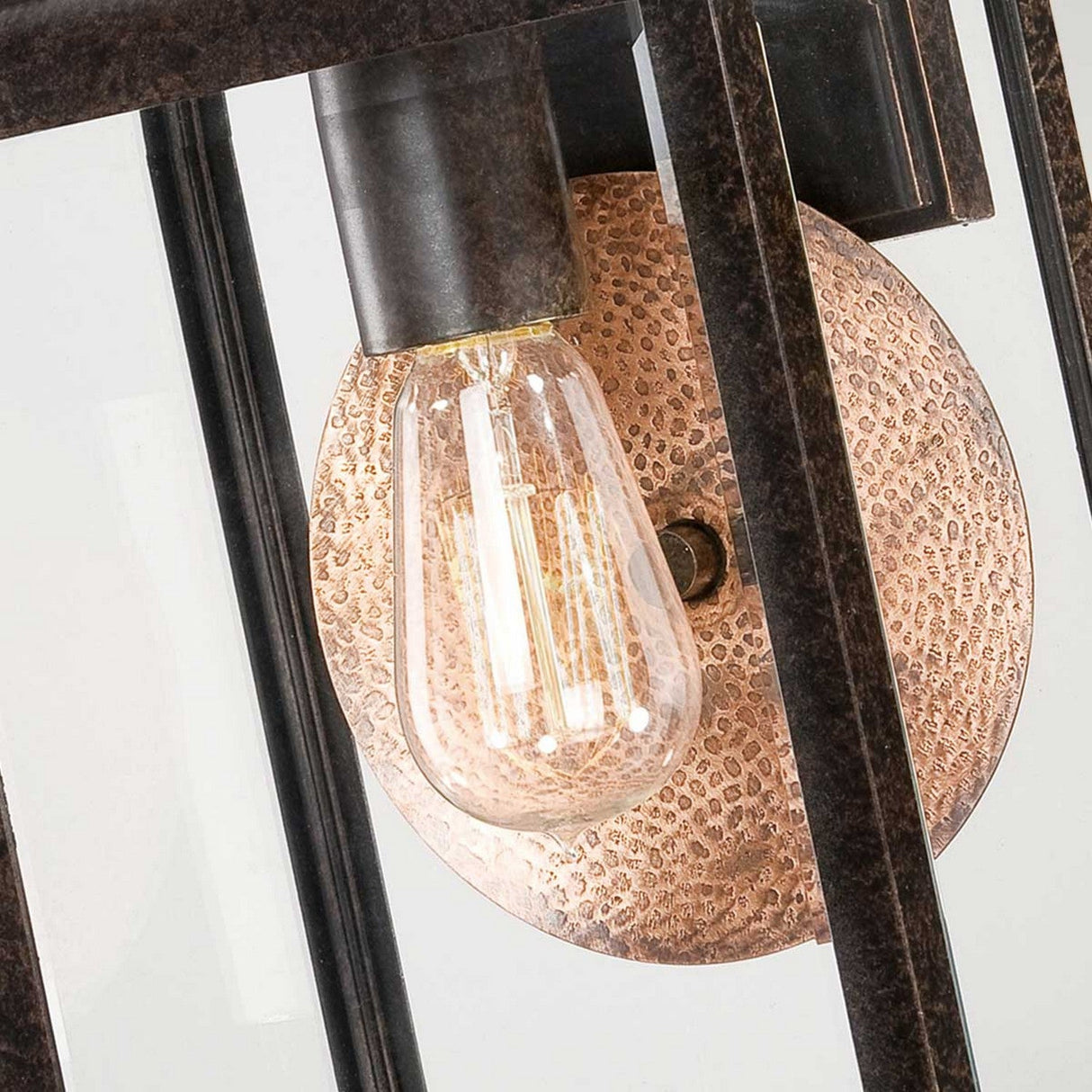 Close-up of the Byron Outdoor 1 Light Medium Wall Lantern, showcasing its industrial design with a vintage Edison bulb. The bulb is enclosed in a dark metal frame finished in Imperial Bronze and complemented by a textured copper reflector, creating a warm and rustic aesthetic.