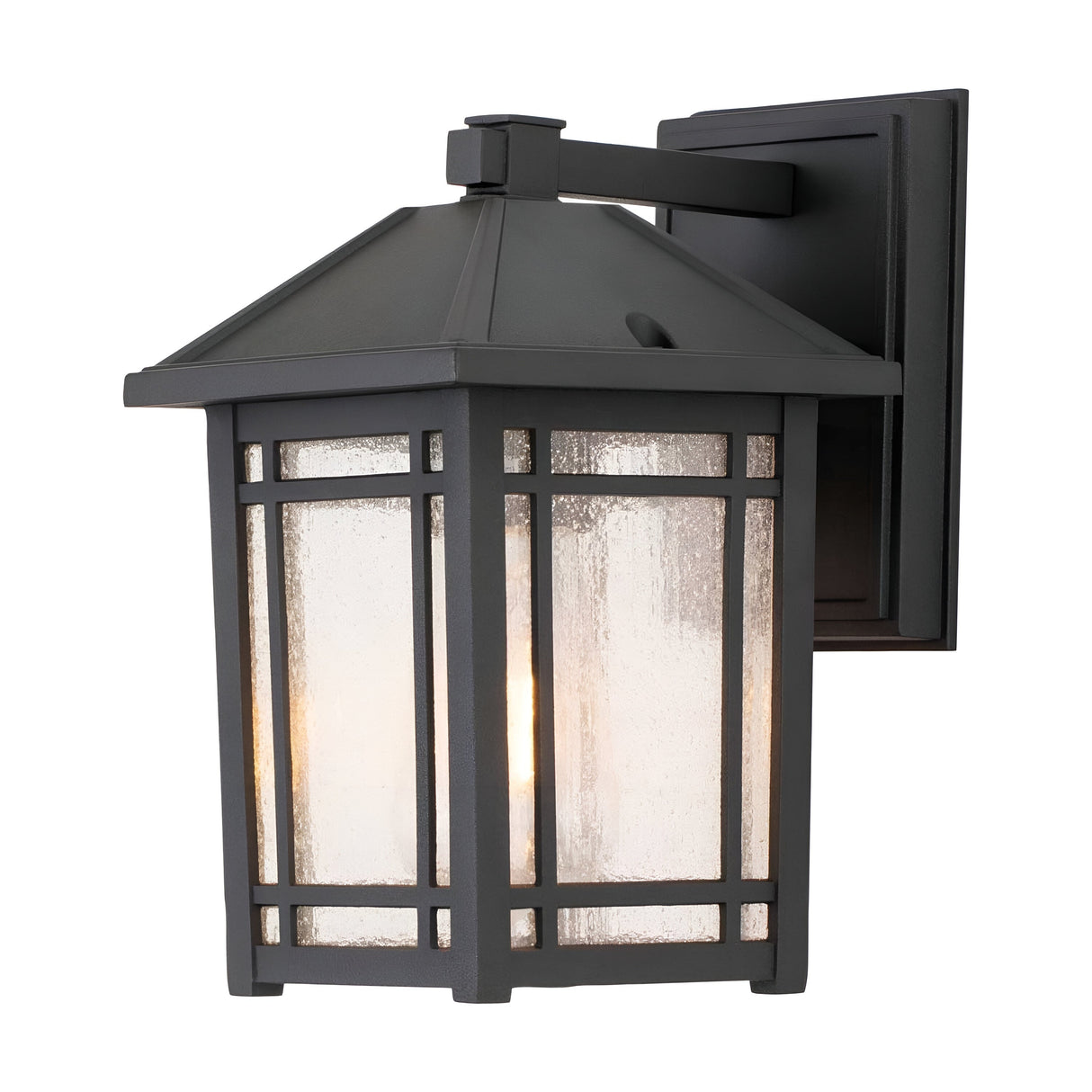 The Cedar Point Outdoor 1 Light Small Wall Lantern - Black features a vintage design with a rectangular metal frame accented by seedy glass panels. Ideal for rustic outdoor lighting, it provides a warm glow and is mounted on a square base with a dark, rustic finish.