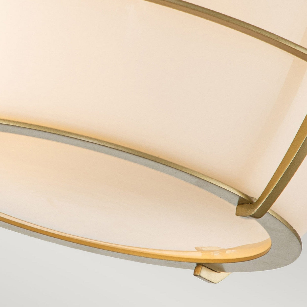 A detailed view of the Chance 2 Light Flush - Natural Brass showcases its contemporary ceiling light fixture with a round, layered design in beige and gold tones. It features smooth, overlapping panels in natural brass that emit a gentle, ambient glow and comes with an IP44 rating for enhanced durability and elegance.