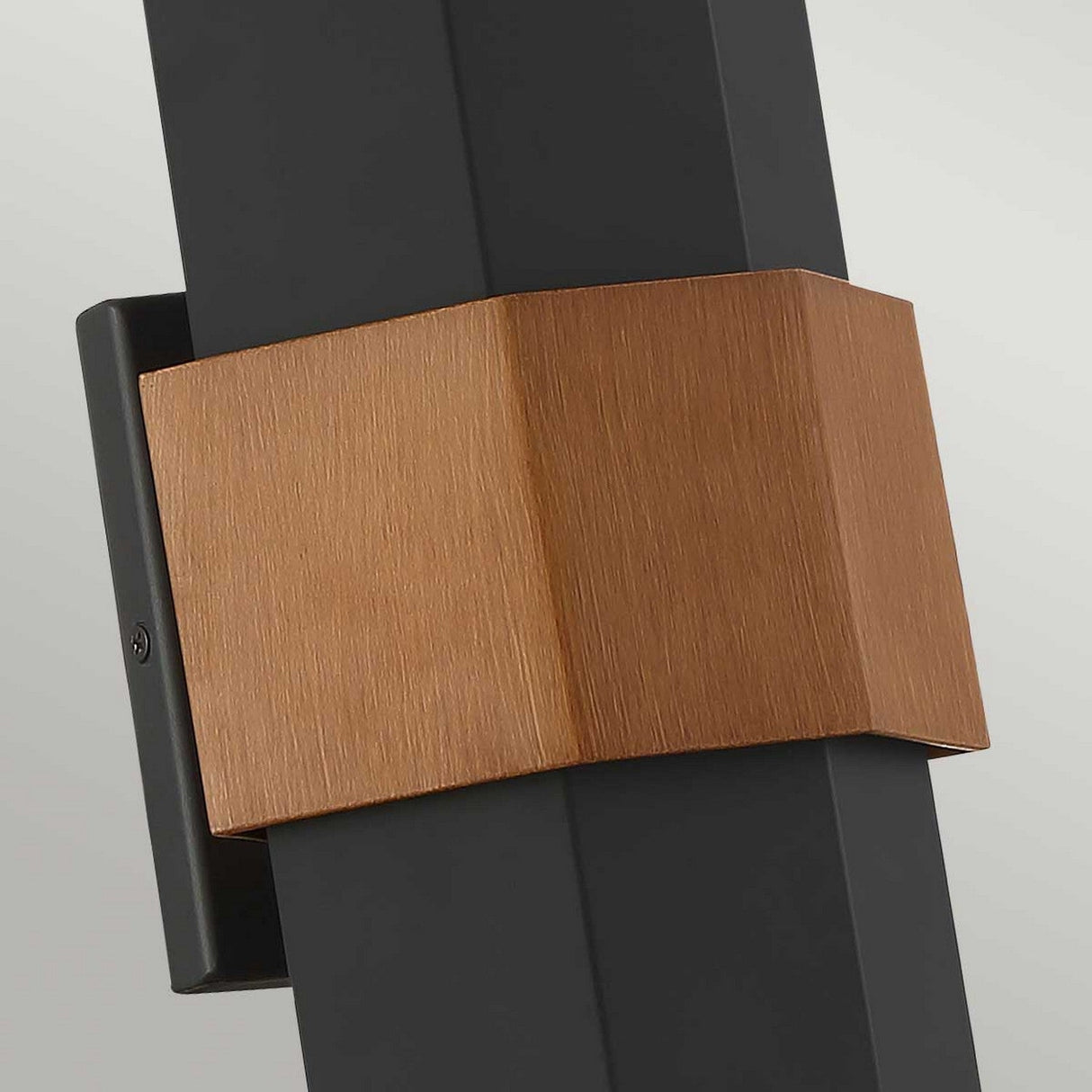 A close-up of the Chasm Outdoor LED Medium Wall Lantern, showcasing its modern design with a matte black base complemented by copper-colored geometric accents. This wall lantern epitomizes minimalism and contemporary style with its sharp angles and energy-efficient lighting.