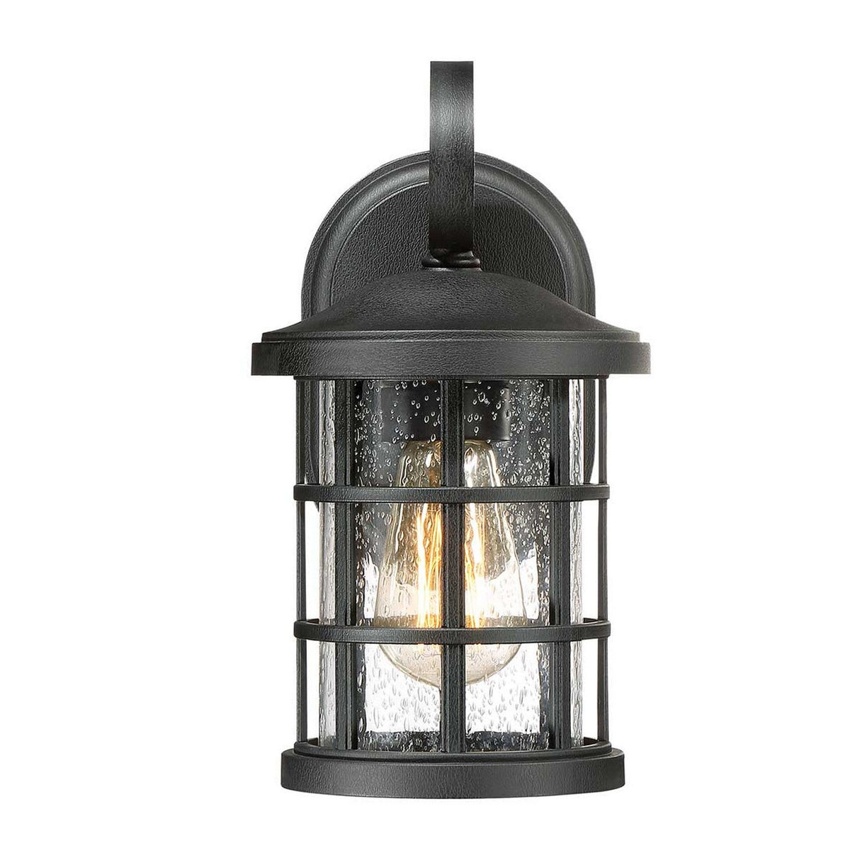 The Crusade Outdoor 1 Light Small Wall Lantern in black features a rustic craftsman design with a cylindrical shape and curved top. It is crafted with a black metal frame and clear seeded glass panels, showcasing an exposed light bulb, all elegantly mounted on a rectangular backplate.