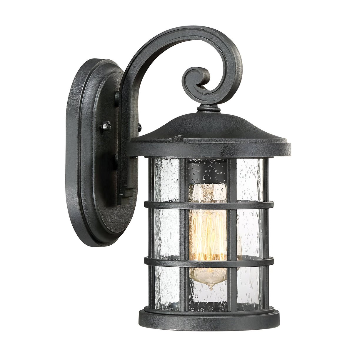 The Crusade Outdoor 1 Light Small Wall Lantern - Black showcases a vintage Craftsman design with its black metal frame and seeded glass panels. The light bulb within provides a warm glow, accentuating its timeless charm.