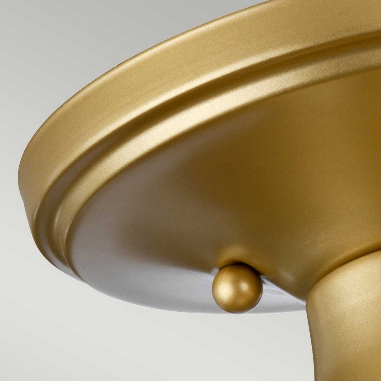 A close-up of a smooth metallic gold lampshade highlights its circular top and small decorative knob, capturing the refined elegance of the Dublin 1 Light Semi Flush - Natural Brass. Set against a neutral background, it is perfect for sophisticated bathroom lighting.