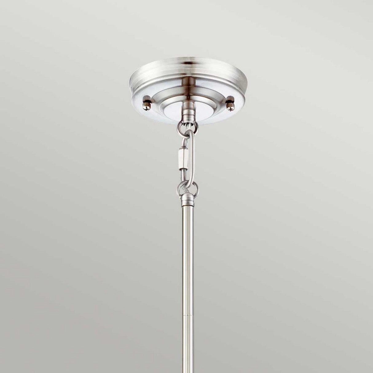 A close-up of an Emery 1 Light Medium Pendant in Imperial Silver features a prismatic lens diffuser. It is mounted on the ceiling with a metal rod against a plain gray background. The fixture showcases a circular base with a sleek, modern design and visible screws for secure attachment.