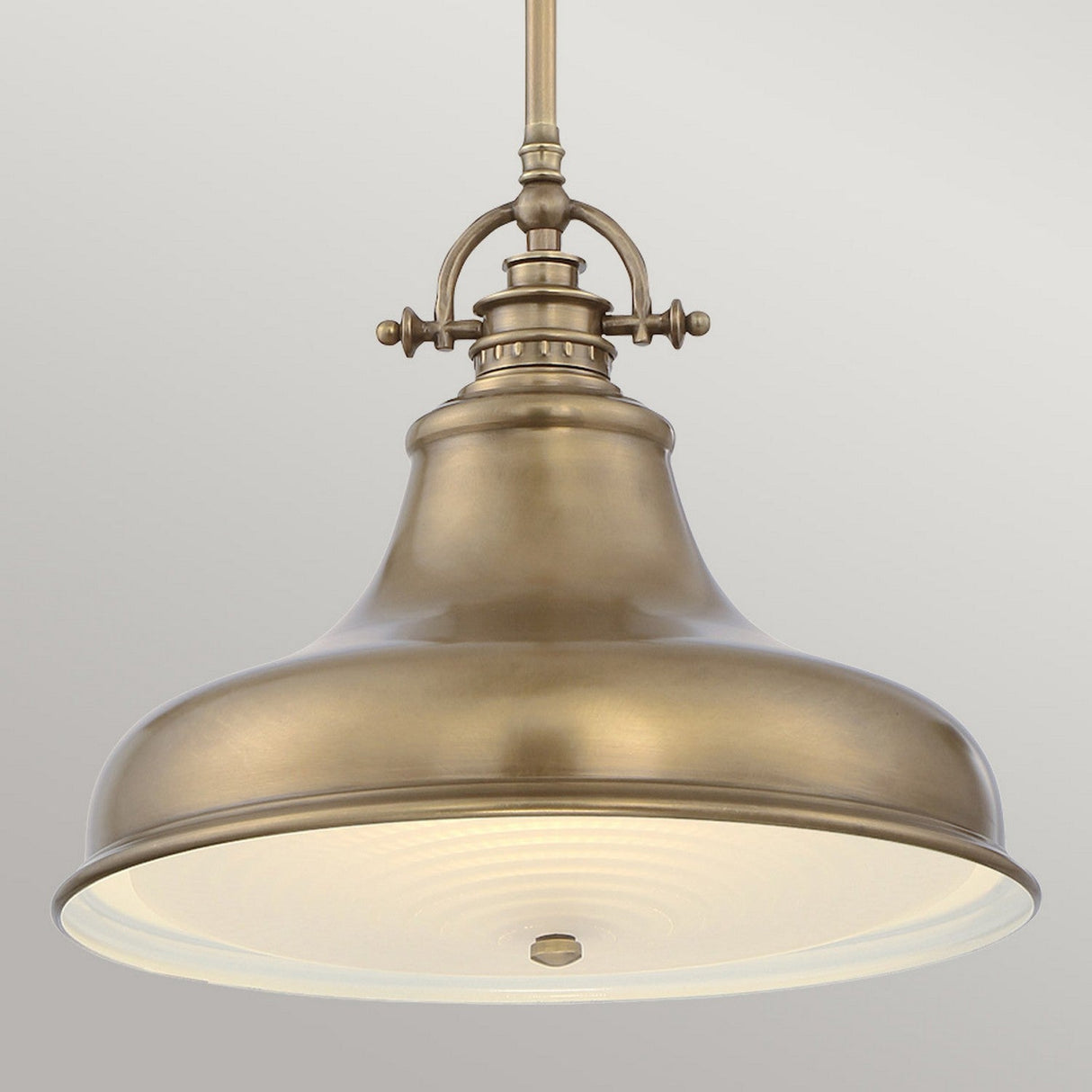 The Emery 1 Light Medium Pendant in weathered brass features a wide, bell-shaped shade and a frosted glass diffuser. Hanging from a matching brass rod against a neutral backdrop, it radiates timeless charm.