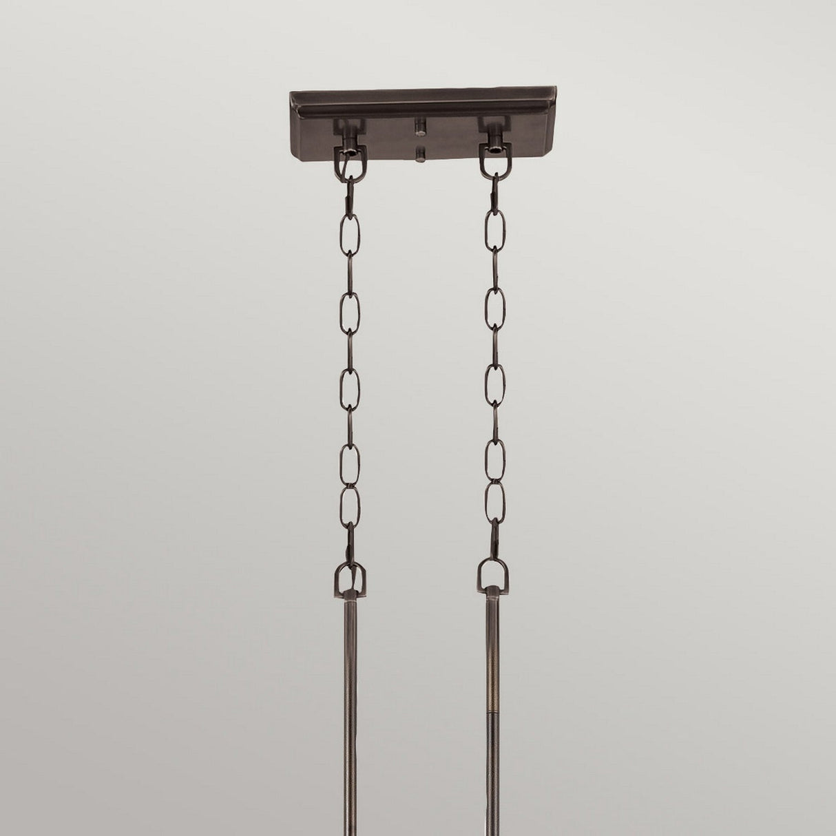 A ceiling mount with the rustic charm of Palladian Bronze features two metal chains attached to a rectangular base, extending downward and ending in rods, set against a plain light gray background. This is the Emery 3 Light Island Pendant - Palladian Bronze.