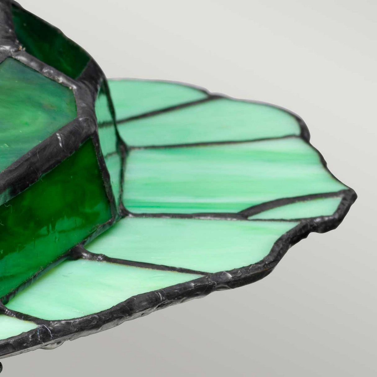 Close-up of the Tiffany Animal Lamps Frog Lamp in vintage bronze, showcasing a scalloped edge with various shades of green and a textured, artistic layered design.