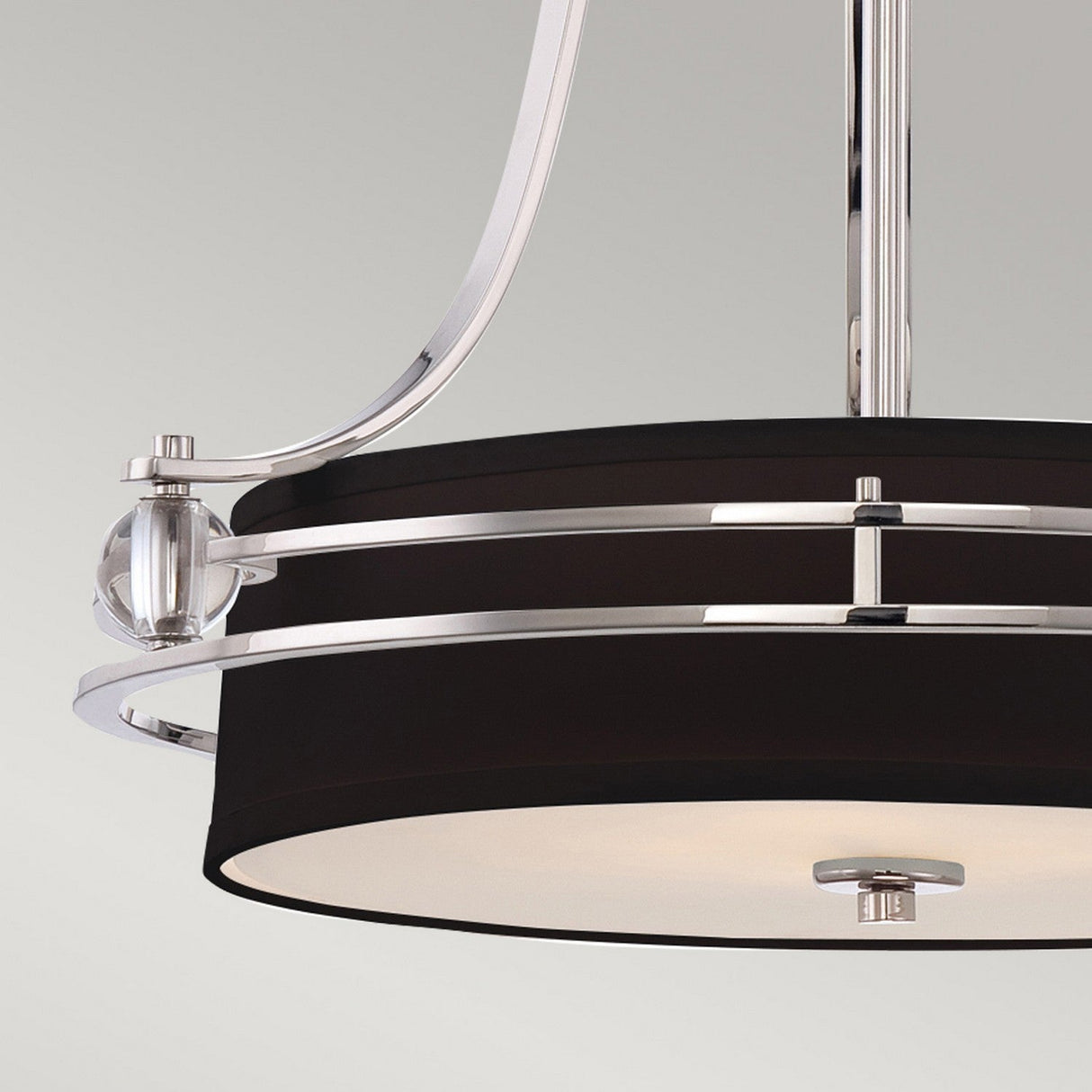 A close-up of the Gotham 4 Light Small Chandelier in Imperial Silver, showcasing its modern circular design with a black and silver finish. This ceiling light fixture features sleek metal accents and a translucent glass cover, all set against a light gray background.
