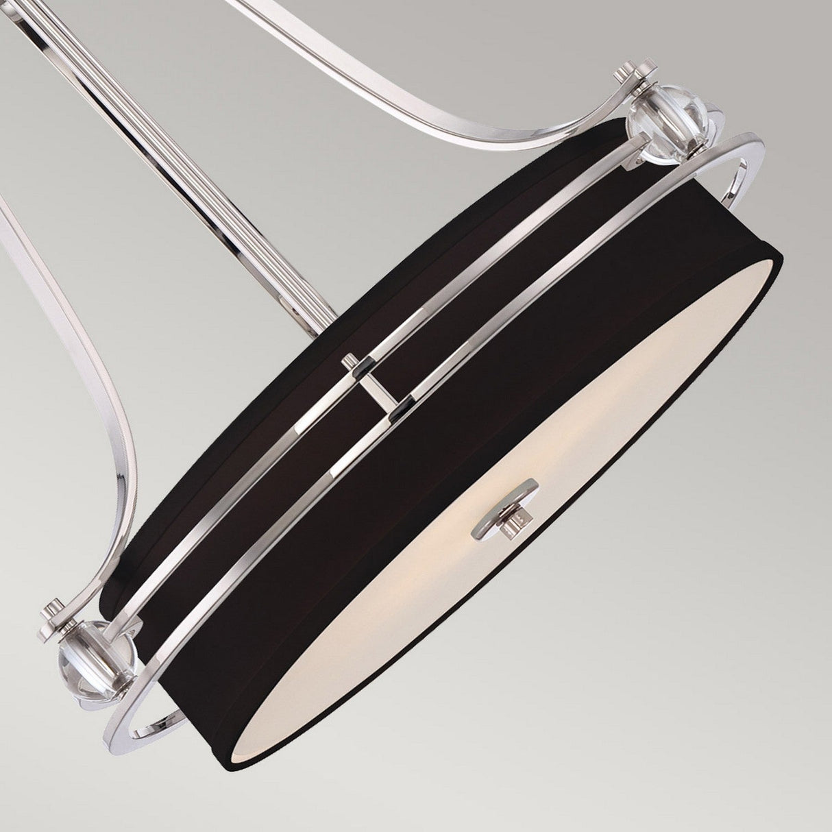 The Gotham 4 Light Small Chandelier - Imperial Silver features a round black outer shade with chrome accents and curved support arms. Its central Imperial Silver frosted diffuser enriches any modern interior, especially against a neutral backdrop.