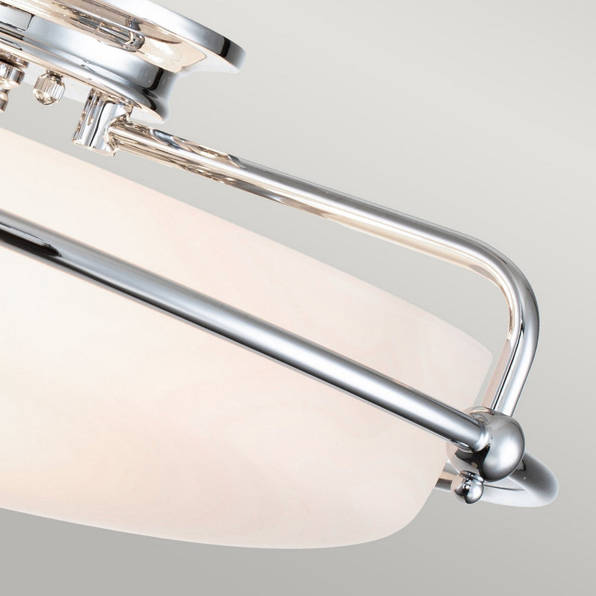 The Griffin 3 Light Flush in Polished Chrome showcases a sleek, polished chrome frame and a frosted glass shade. This contemporary lighting design features elegantly curved metal bars supporting the shade, set beautifully against a neutral gray background, exuding understated sophistication.