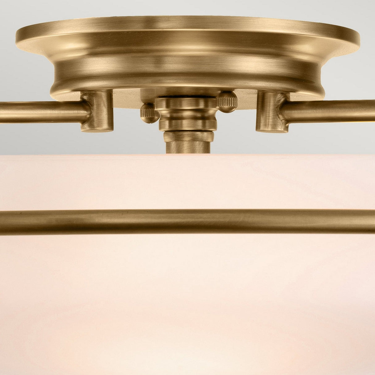 The Griffin 3 Light Flush in Weathered Brass showcases a close-up view of its ceiling light fixture, with an etched glass shade and classic design elements such as visible screws and support rods. Its warm, metallic finish makes it ideal for transitional interiors.