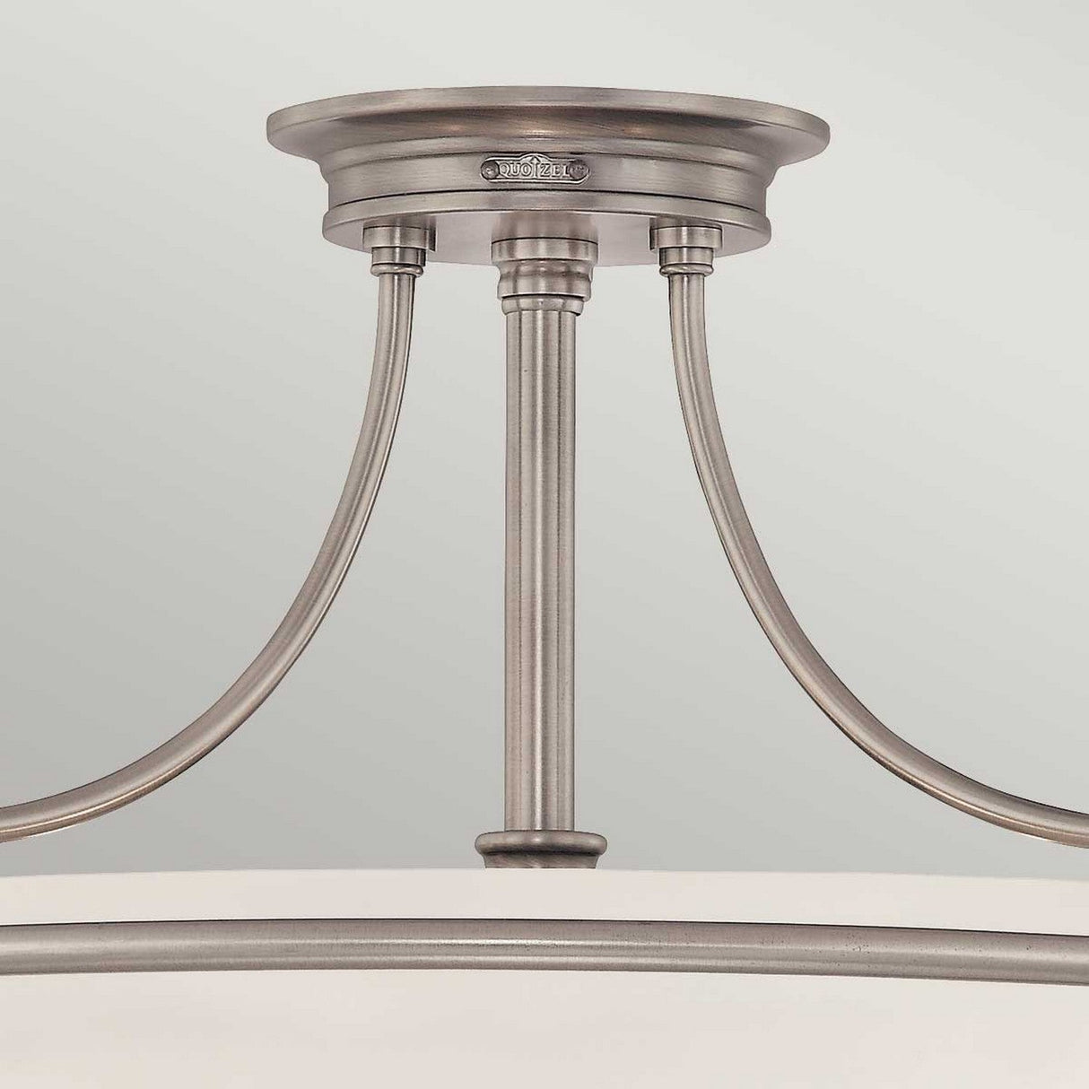 The Griffin 4 Light Semi-Flush in Antique Nickel boasts a sleek, modern design with a round base and two elegantly curved arms supporting a central rod, providing ambient lighting that complements a light gray background beautifully.