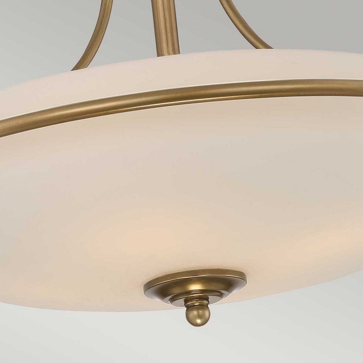 Close-up of the Griffin 4 Light Semi-Flush in Weathered Brass, showcasing its round frosted glass shade and delicate weathered brass accents. This fixture includes a decorative finial at the bottom, providing ambient lighting with an elegant and understated look.