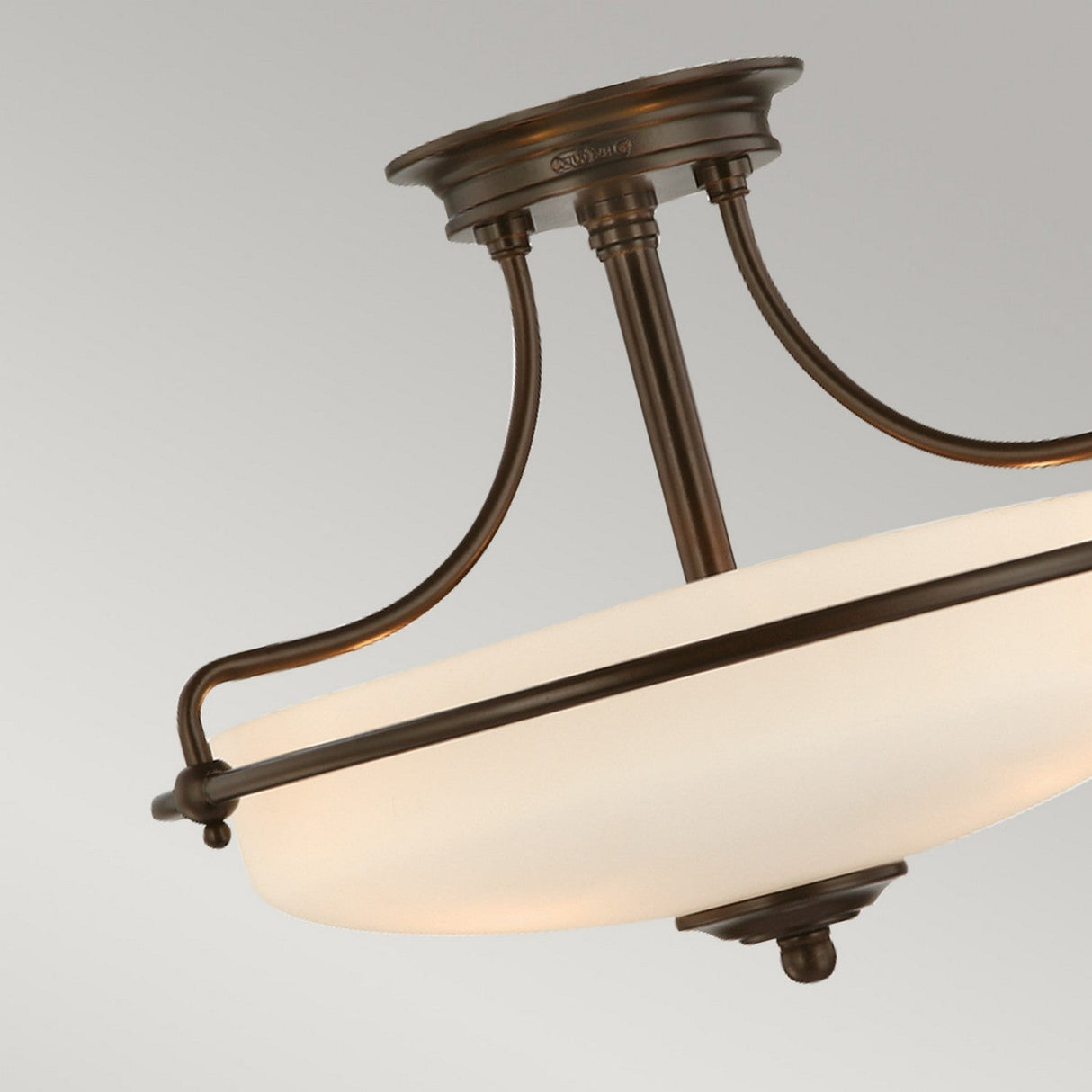 The Griffin 3 Light Semi-Flush in Palladian Bronze showcases three gracefully curved arms that elegantly hold a white frosted glass bowl, providing ambient lighting against a simple backdrop.