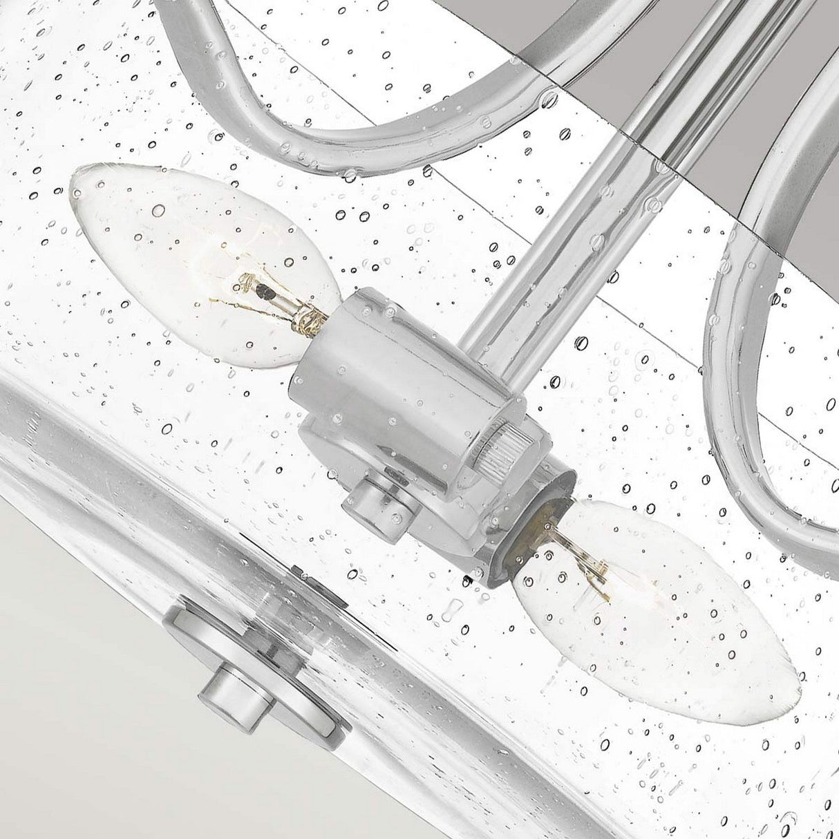 A close-up of the Hollister 2 Light Semi-Flush in polished nickel showcases its modern design with a pristine finish and a seeded glass shade. The two visible light bulbs, encased in a clear cover, are accentuated by water droplet details, creating a fresh and sleek aesthetic.