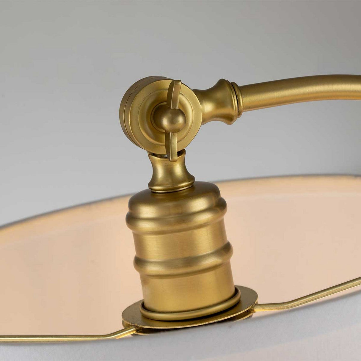 A close-up of the Jenkins 1 Light Table Lamp - Brushed Brass showcases the adjustable joint and a portion of the linen shade's edge. The brushed brass finish exudes modern elegance with its warm, golden tone set against a neutral backdrop.