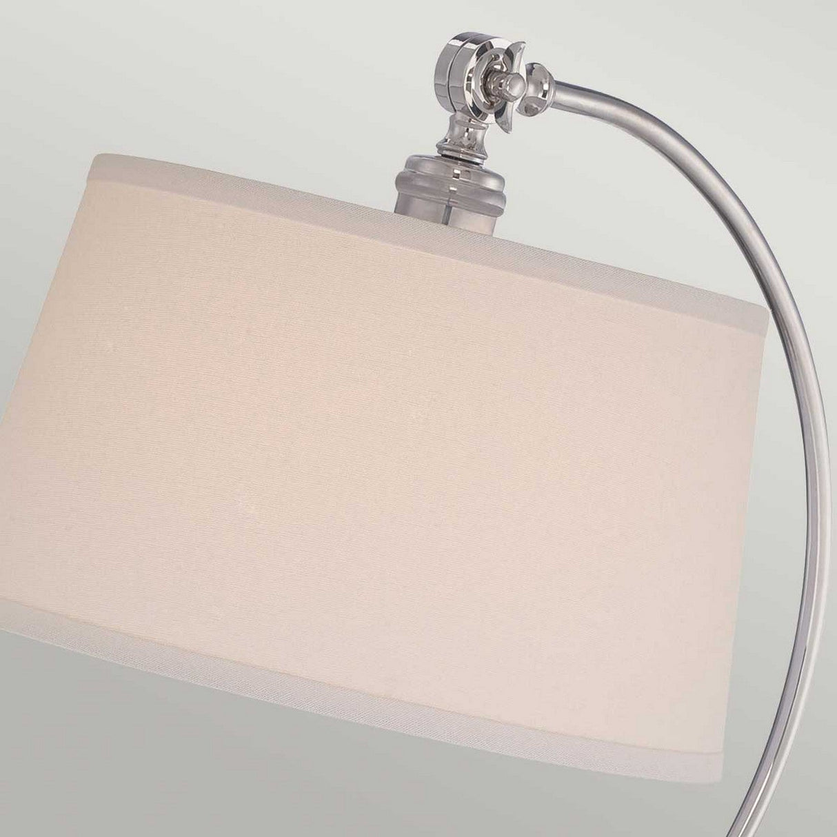The Jenkins 1 Light Table Lamp in polished nickel features a curved silver metal stand and an elegant, large cream-colored drum-shaped lampshade. This stylish piece beautifully complements contemporary decor, standing out against a light gray background.