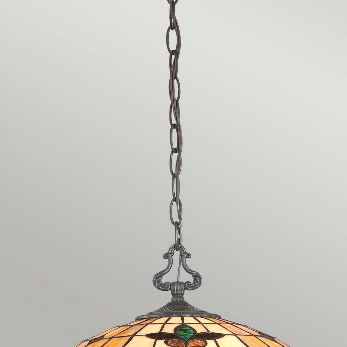 The Kami 3 Light Tiffany Pendant in Vintage Bronze showcases a vintage-style design with a stained glass shade consisting of warm-toned glass and green accents. This hanging light fixture features intricate metalwork in vintage bronze and includes a decorative chain, lending timeless elegance to any space.