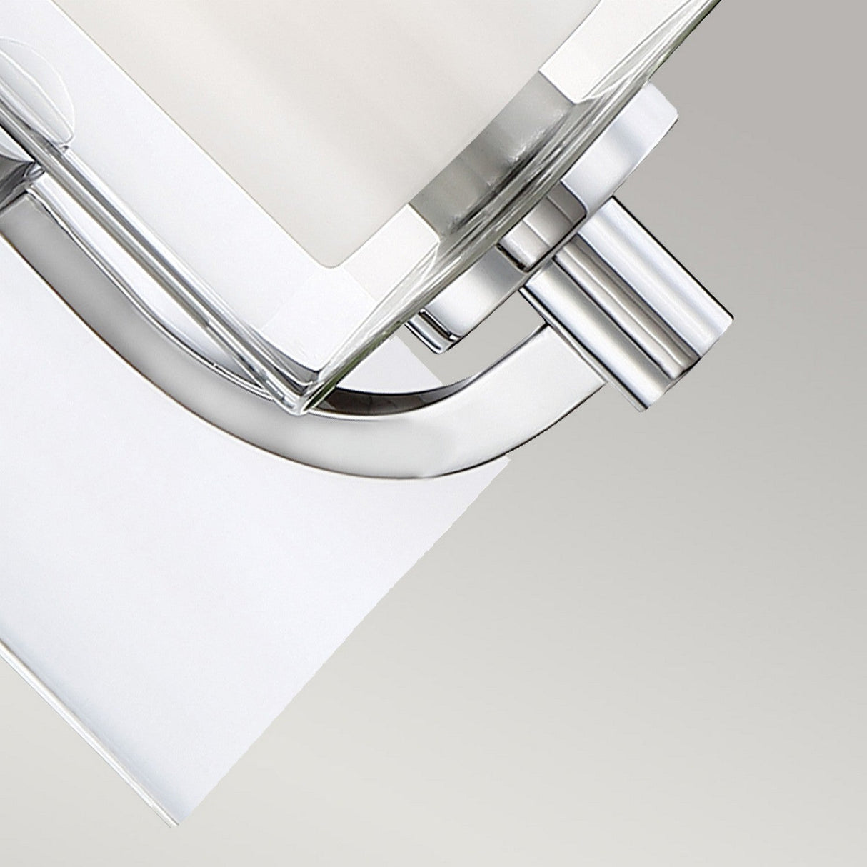 A close-up view of the Kolt 1 Light Wall Light in polished chrome showcases its sleek lines and minimalist aesthetic, reminiscent of a modern chrome toilet paper holder against a neutral background.