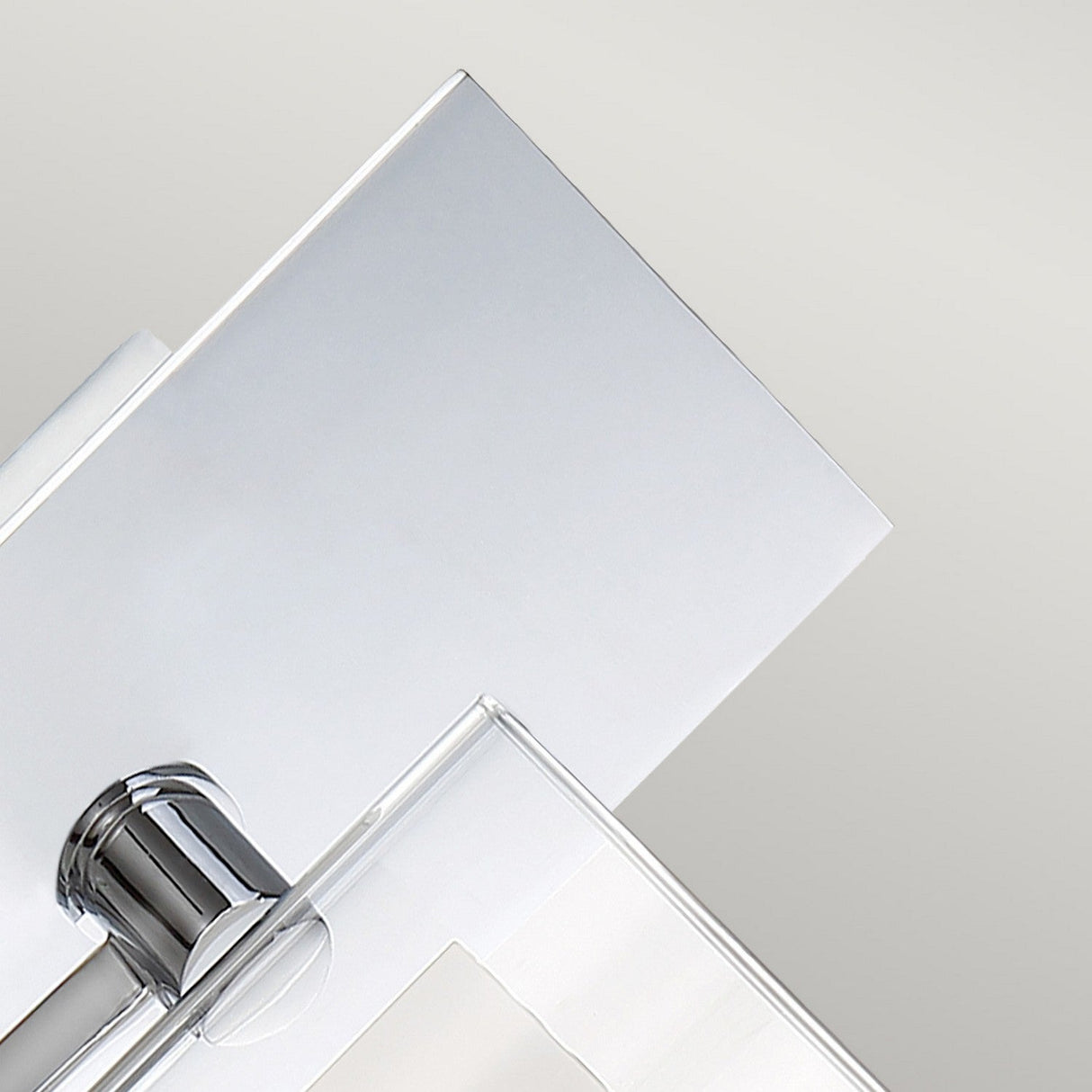 Close-up of a minimalist, modern faucet with geometric lines and a polished silver finish. The backdrop features a soft gradient of light gray, accentuating the faucet's sleek design alongside the Kolt 1 Light Wall Light in polished chrome that adds an elegant touch to this contemporary bathroom setting.