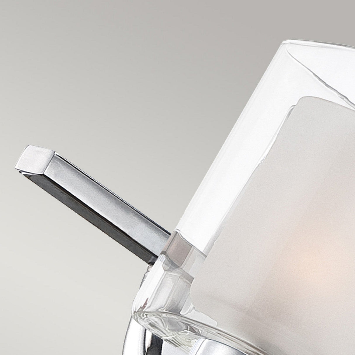Close-up of the Kolt 2 Light Wall Light in polished chrome, showcasing a modern wall-mounted design with a cylindrical frosted dual-layer glass shade. The light gently illuminates from within, making it ideal for enhancing bathroom lighting against a neutral background.