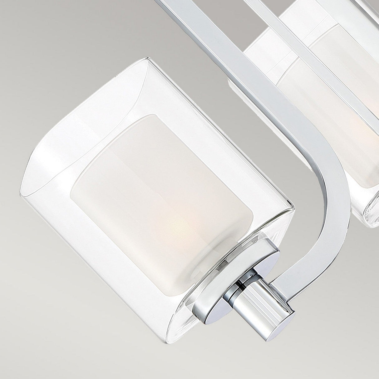 The Kolt 3 Light Wall Light in Polished Chrome is a modern fixture featuring a sleek, curved metal arm and a square-shaped frosted dual-glass design. Its minimalist aesthetic emphasizes clean lines and a metallic finish, making it an ideal choice for sophisticated bathroom lighting.